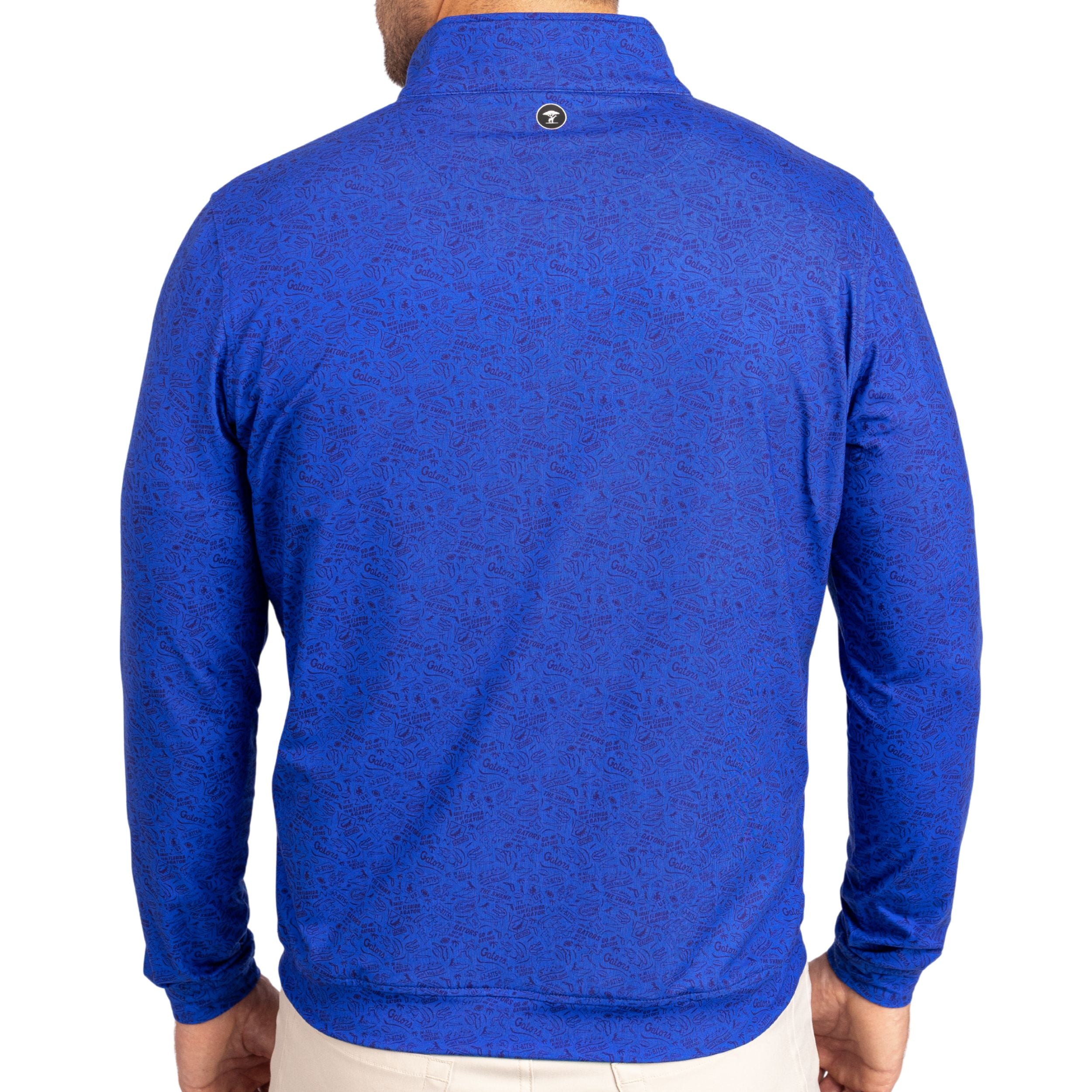 A man viewed from the back wearing a royal blue long-sleeve quarter-zip pullover with a subtle tonal pattern, paired with light beige pants against a white background.