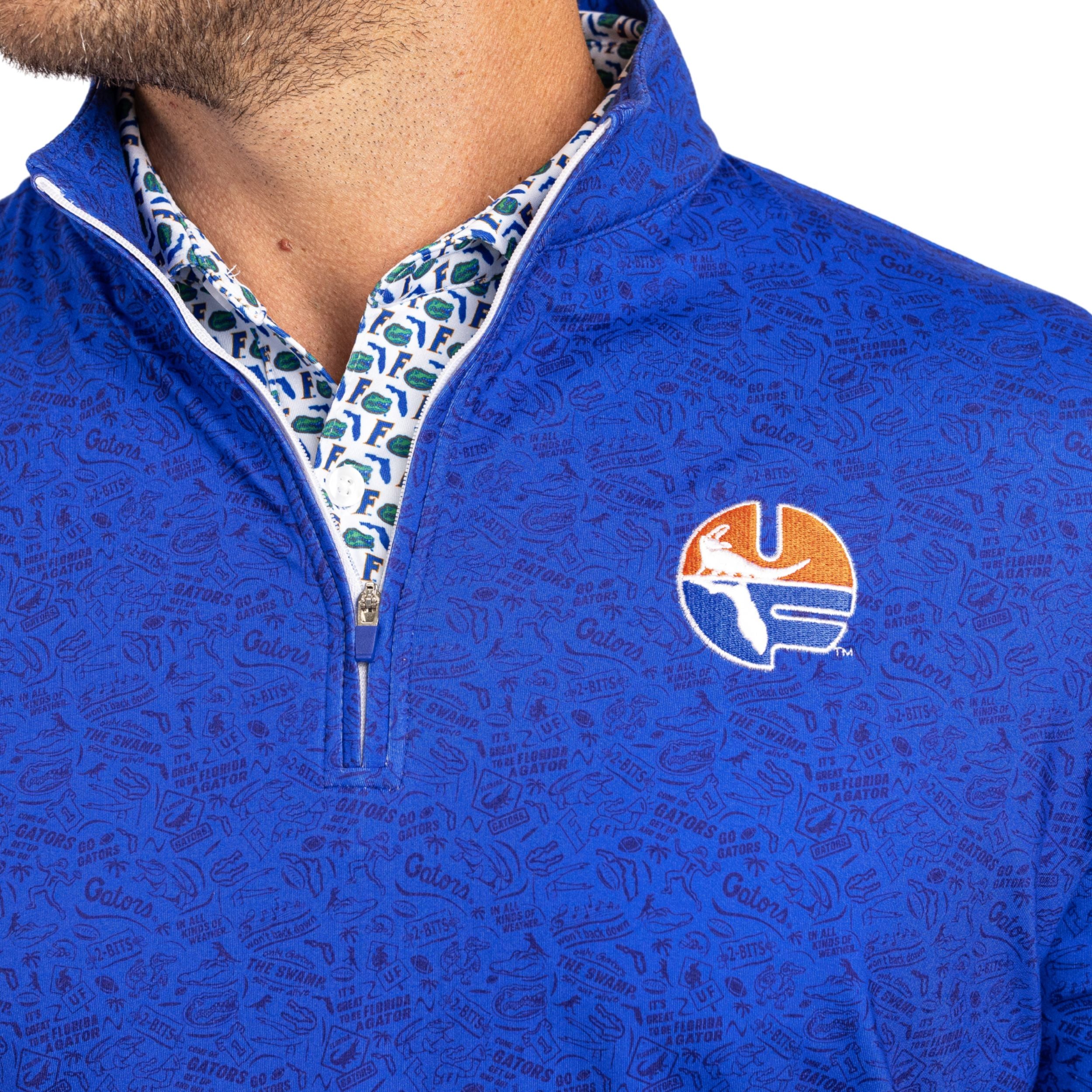 Close-up of a man wearing a royal blue patterned quarter-zip pullover with a Florida Gators logo on the chest, showing the inner collar with a blue, white, and green pattern.