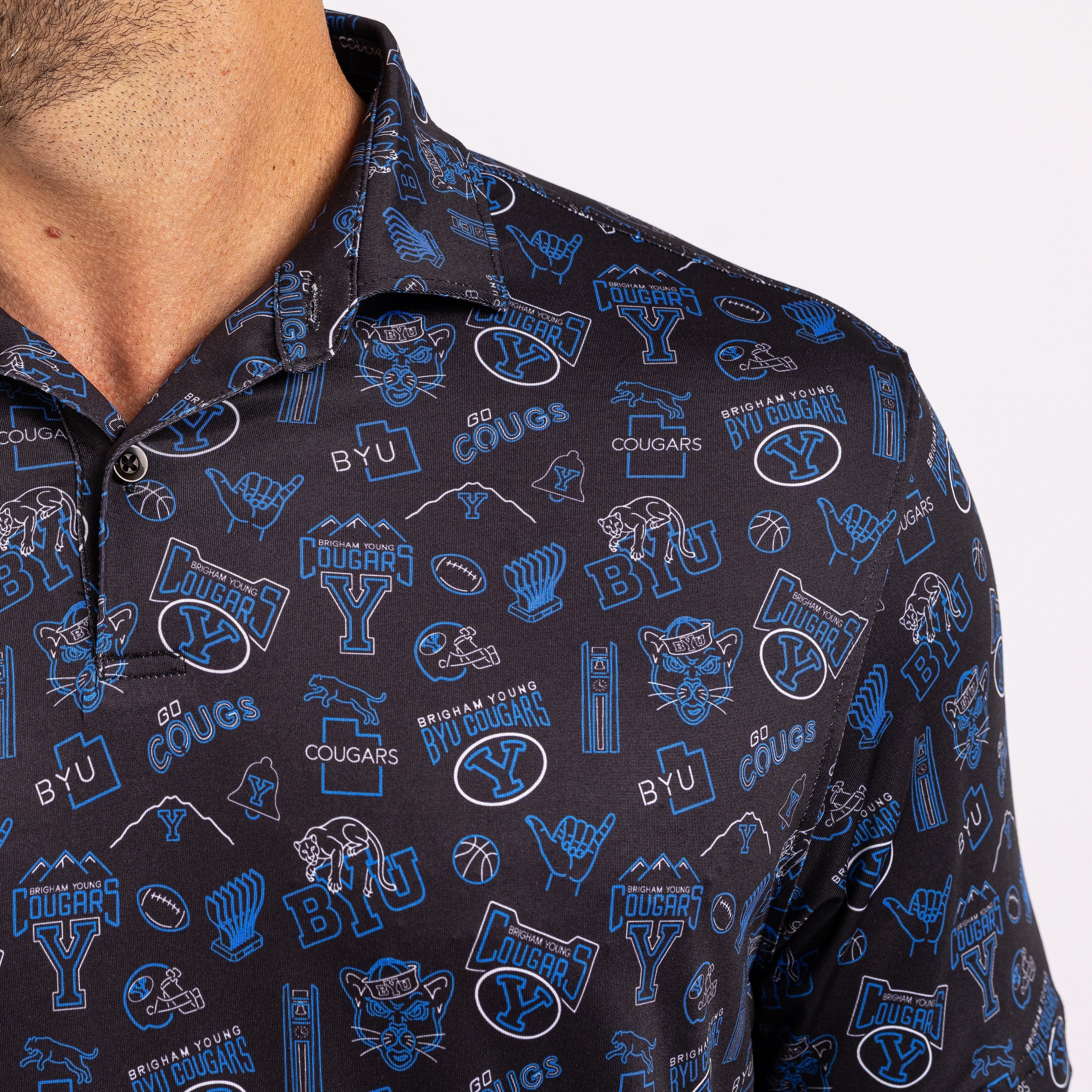 Close-up of a man wearing a dark navy polo shirt with a blue and white 'BYU Cougars' athletic graphic print.