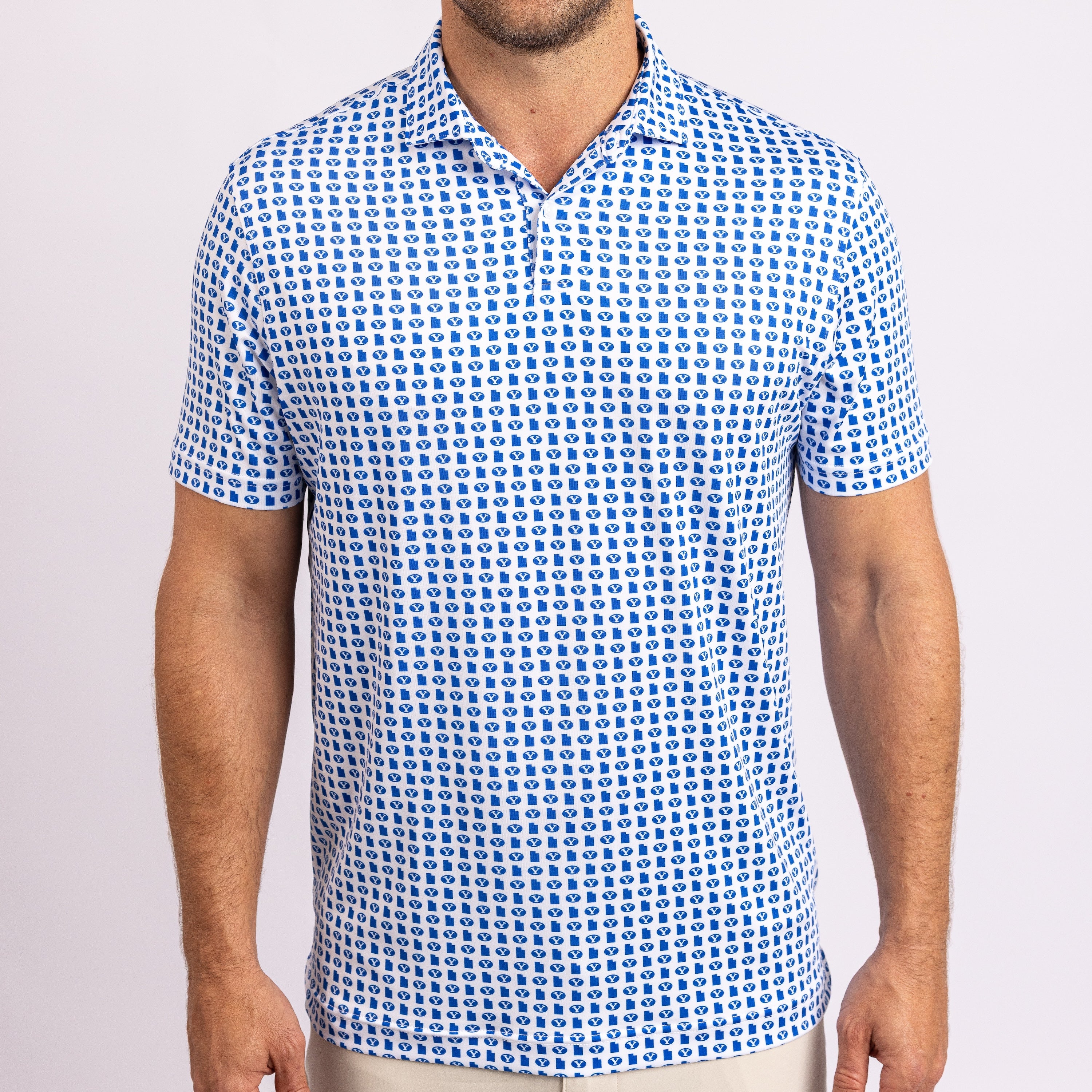 A man wearing a short-sleeve polo shirt with a blue and white pattern, shown from the chin down against a light gray studio background.