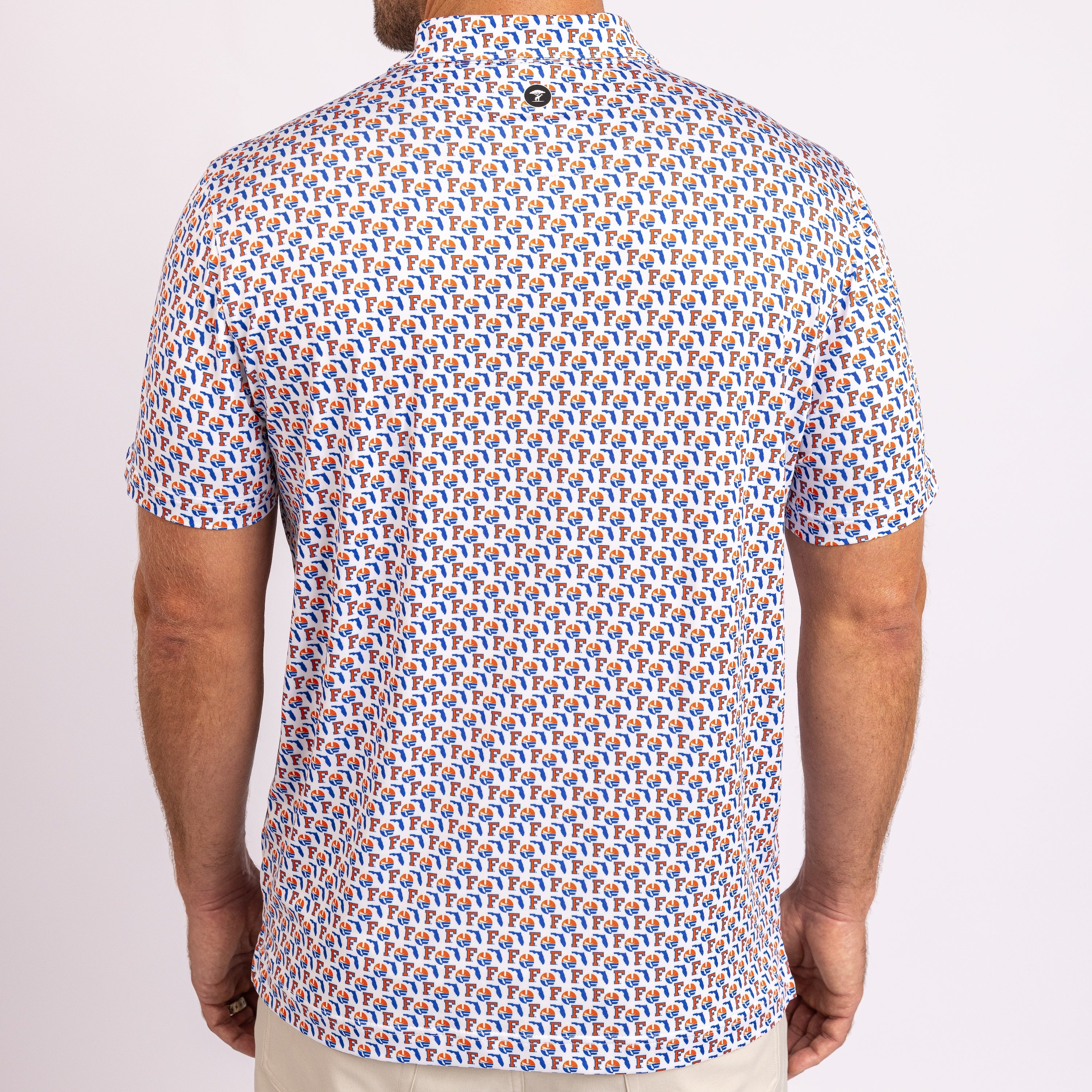 A man viewed from the back wearing a short-sleeve button-up shirt with a dense repeating geometric pattern in blue, orange, and white