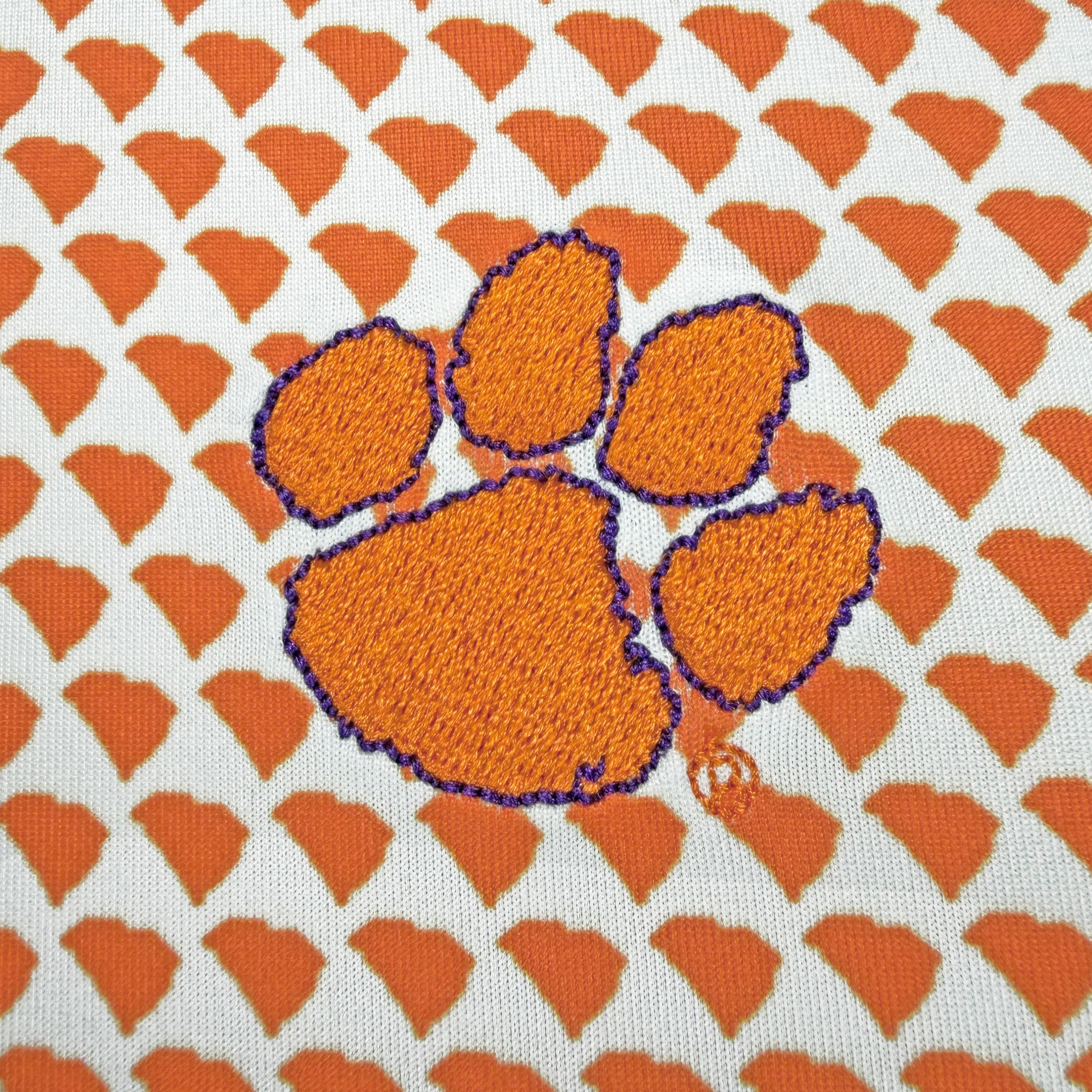 Embroidered paw print design on a fabric with orange and white pattern