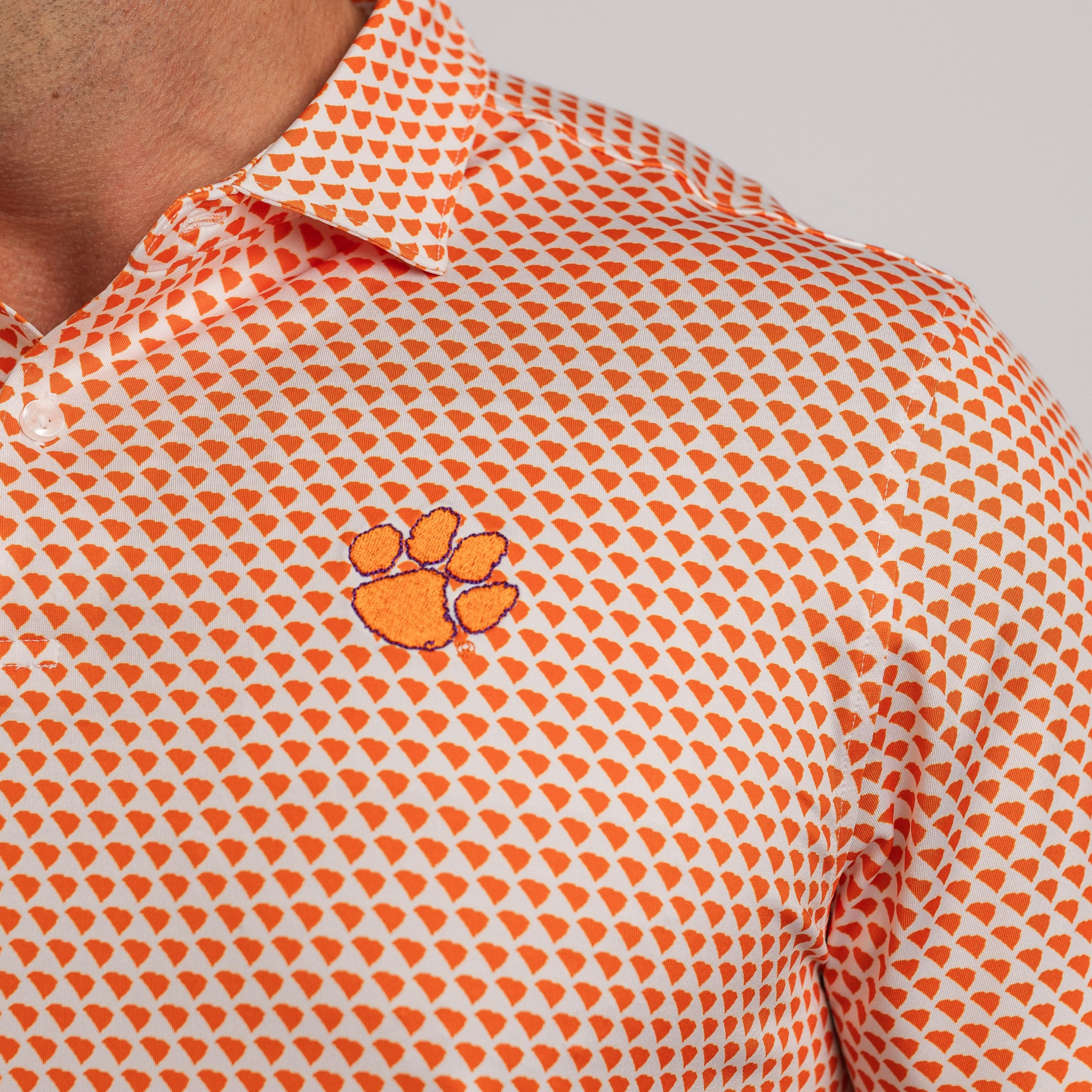 Orange and white patterned polo shirt with a logo on a gray background