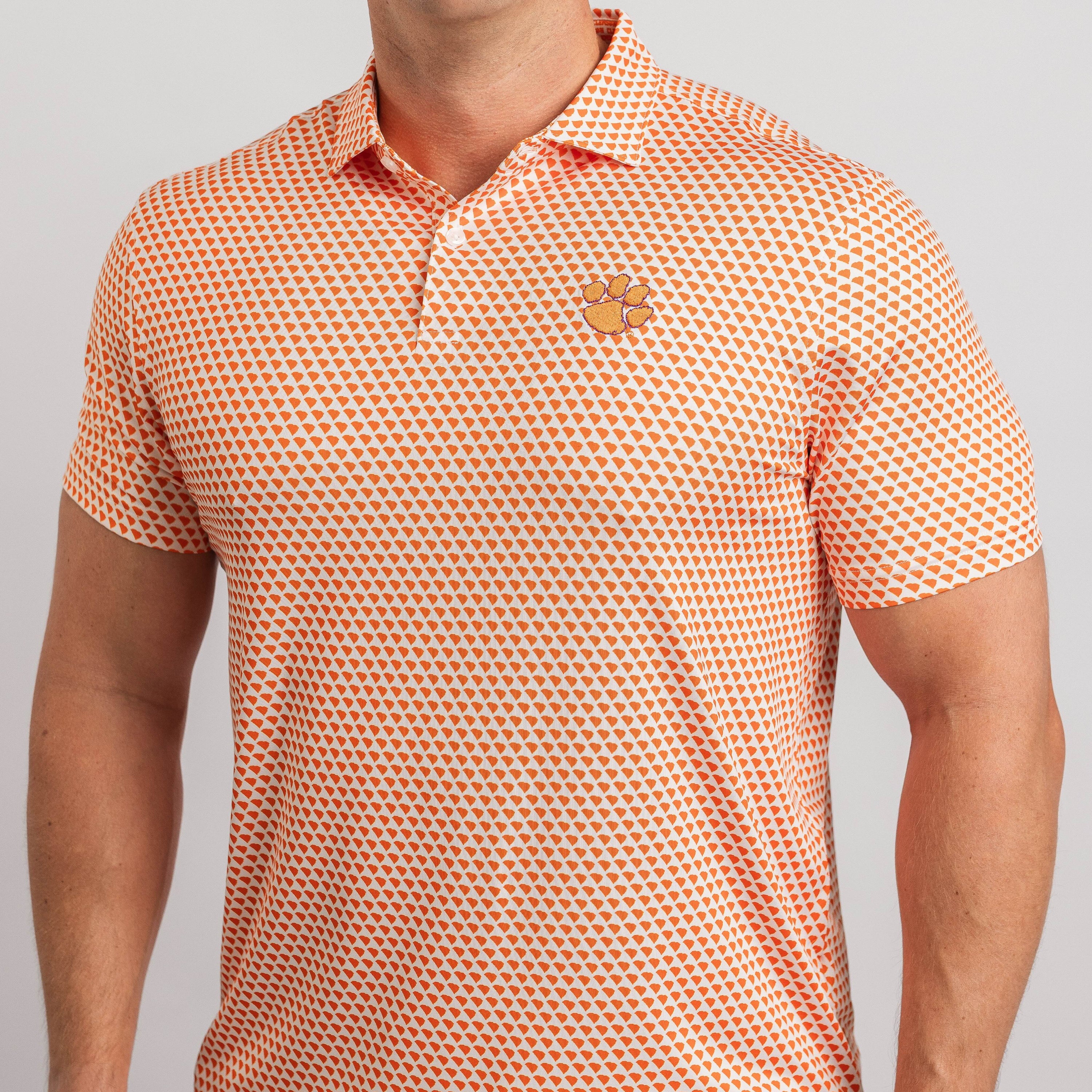 Man wearing an orange and white patterned polo shirt with a logo on a light gray background