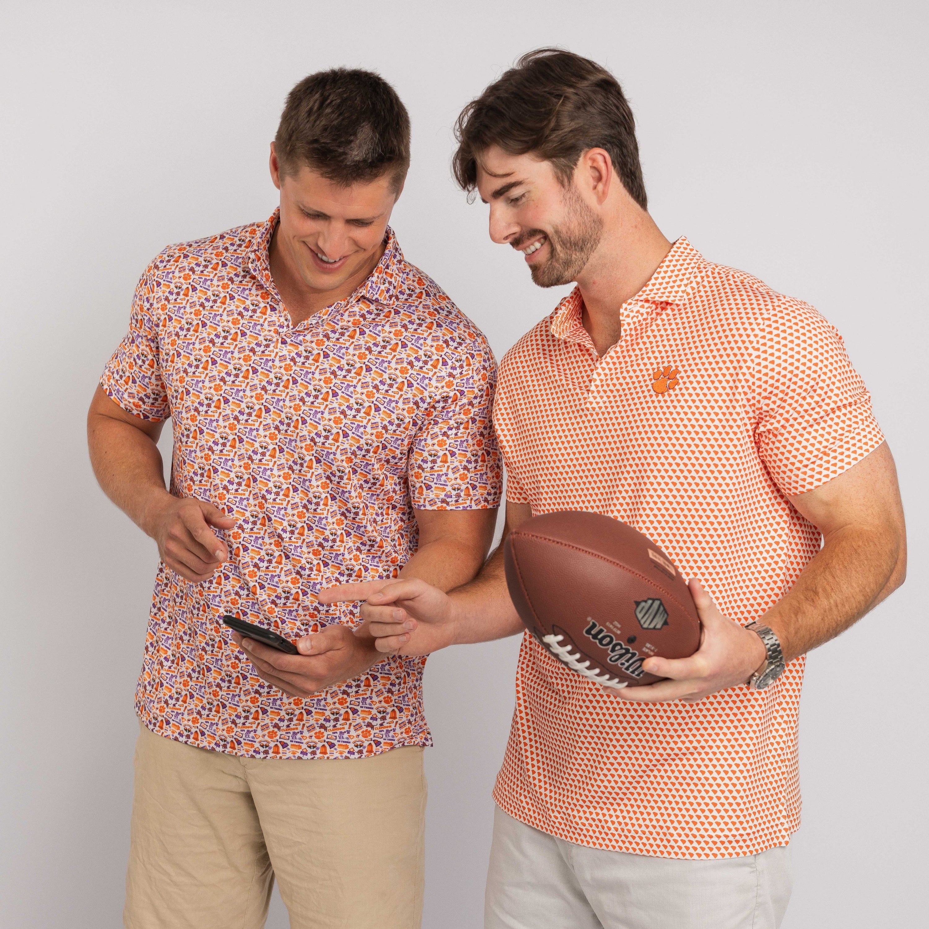 Two men, one holding a football and the other looking at a phone, against a plain background