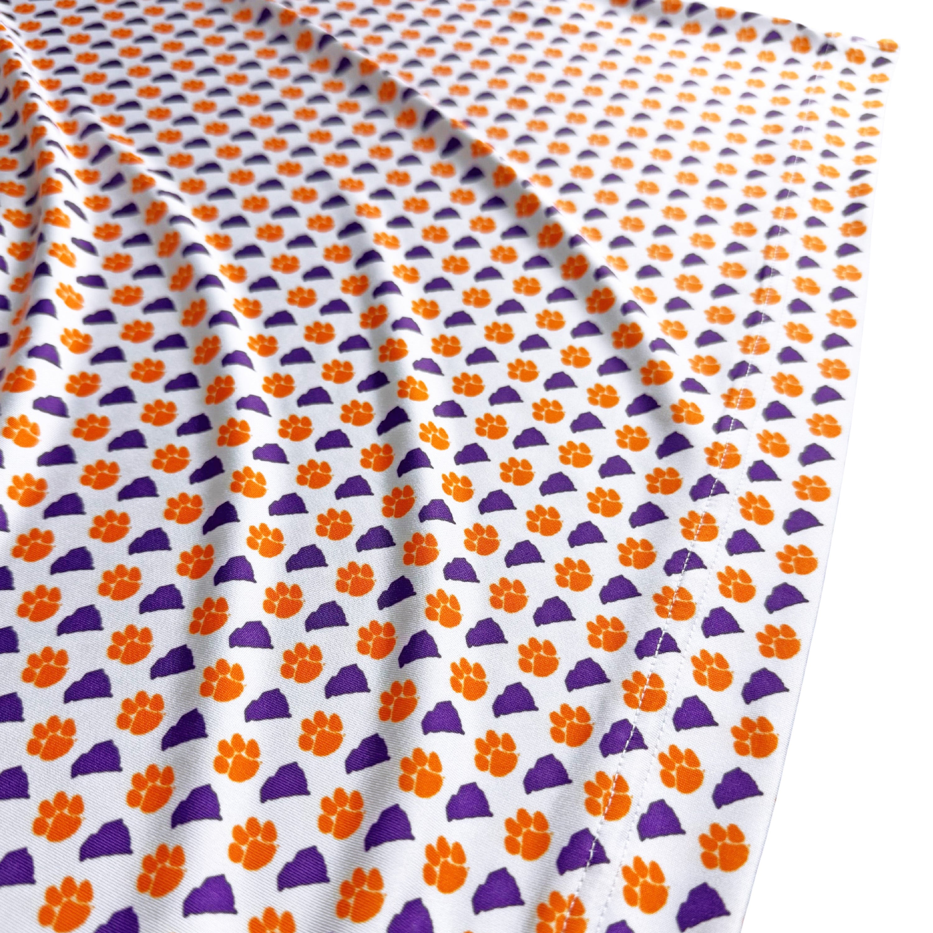 Fabric with orange and purple paw print pattern on a white background