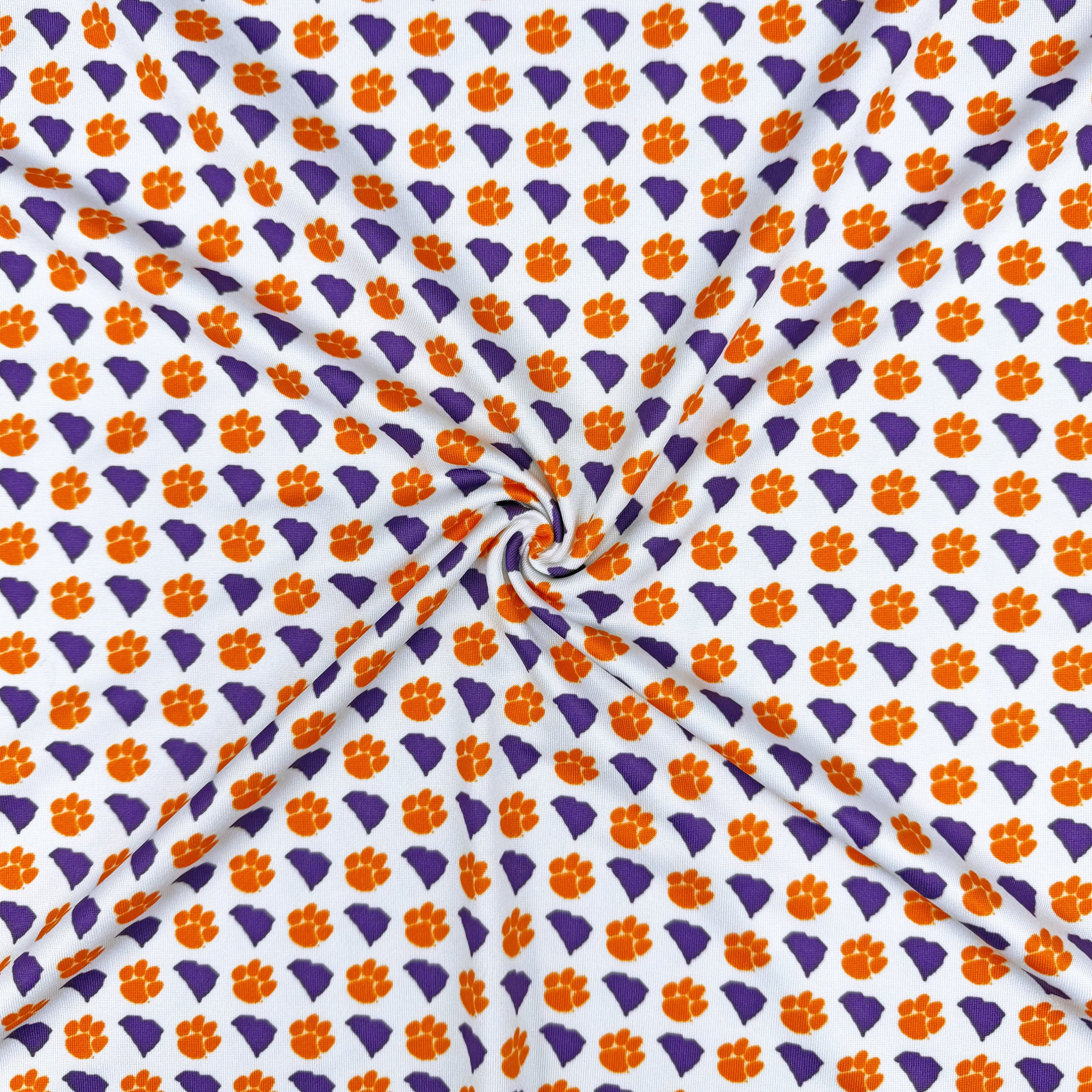 Patterned fabric with orange paw prints and purple shapes on a white background