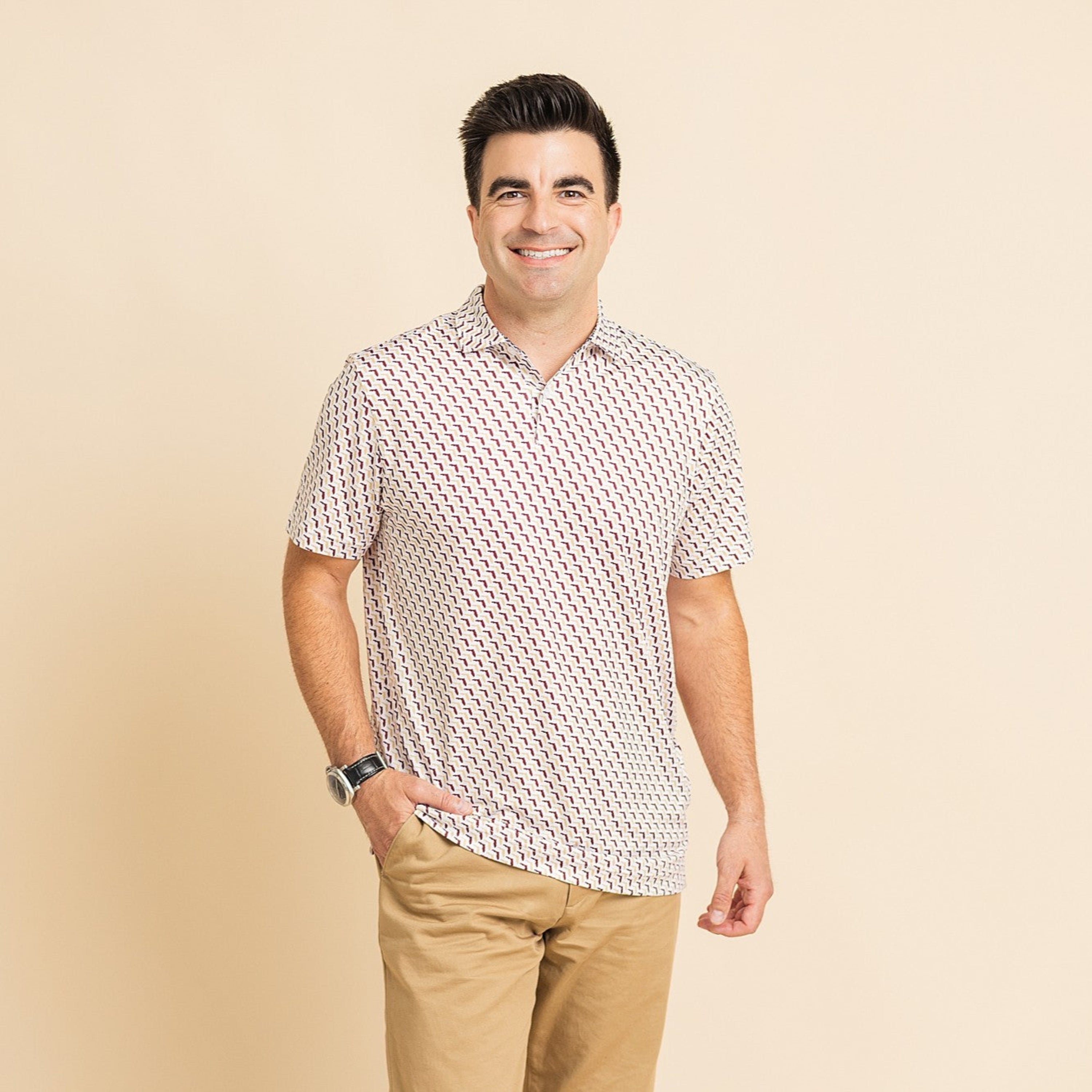 Man wearing a patterned shirt and beige pants on a beige background