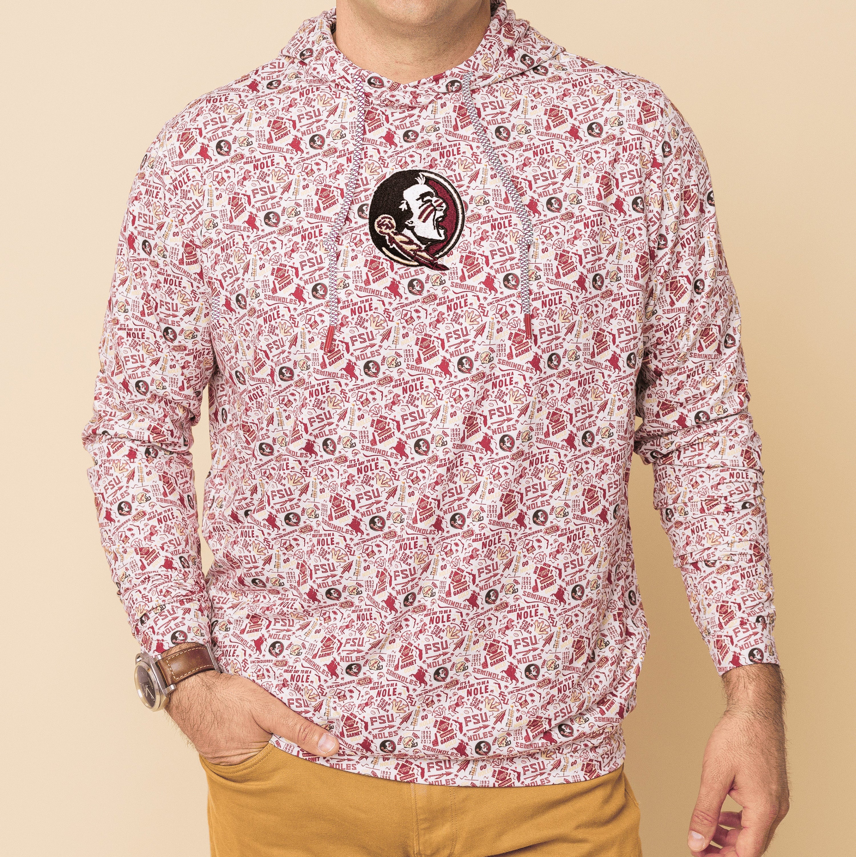 Man wearing a patterned shirt with a logo on a beige background