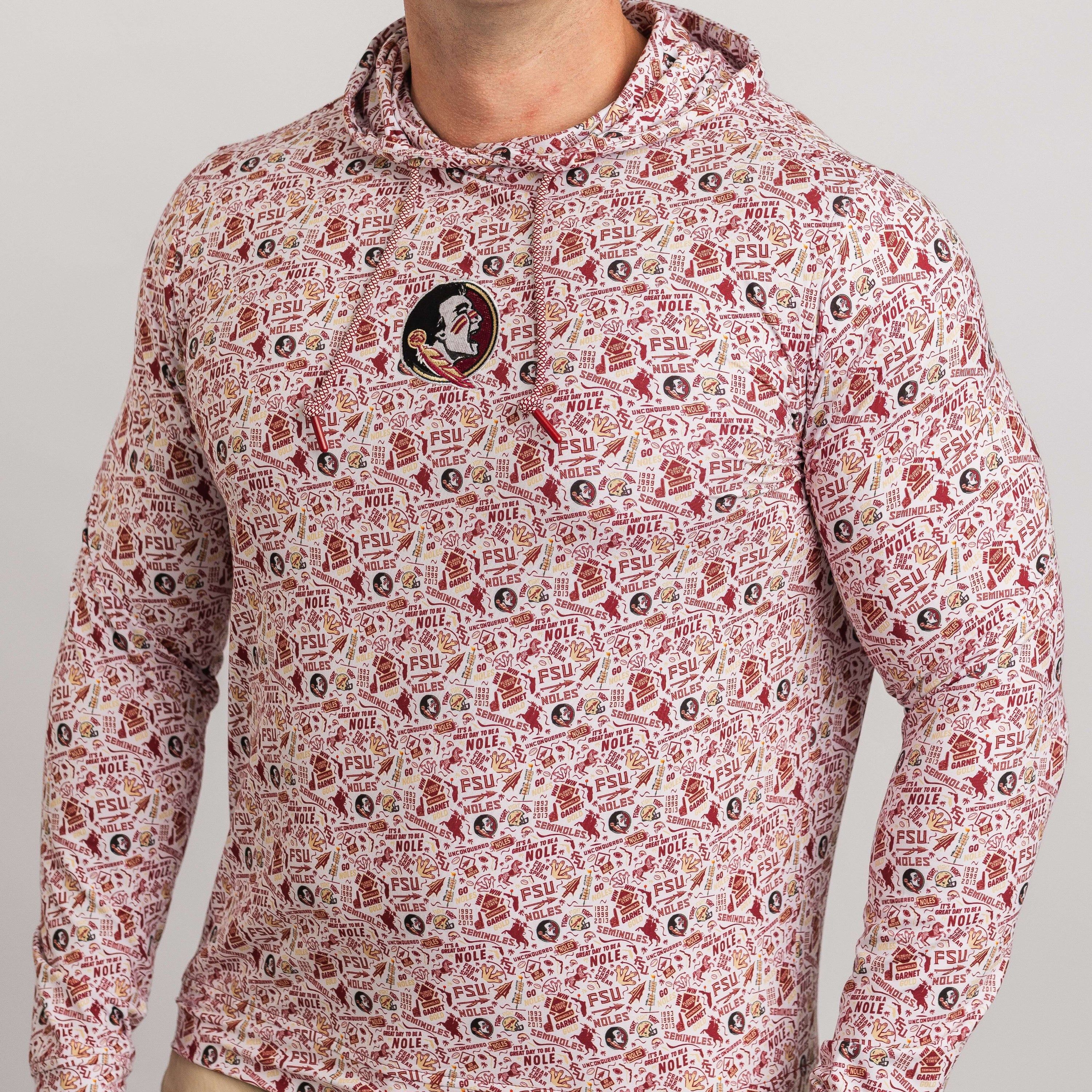 Person wearing a patterned hoodie with a visible brand logo on a gray background