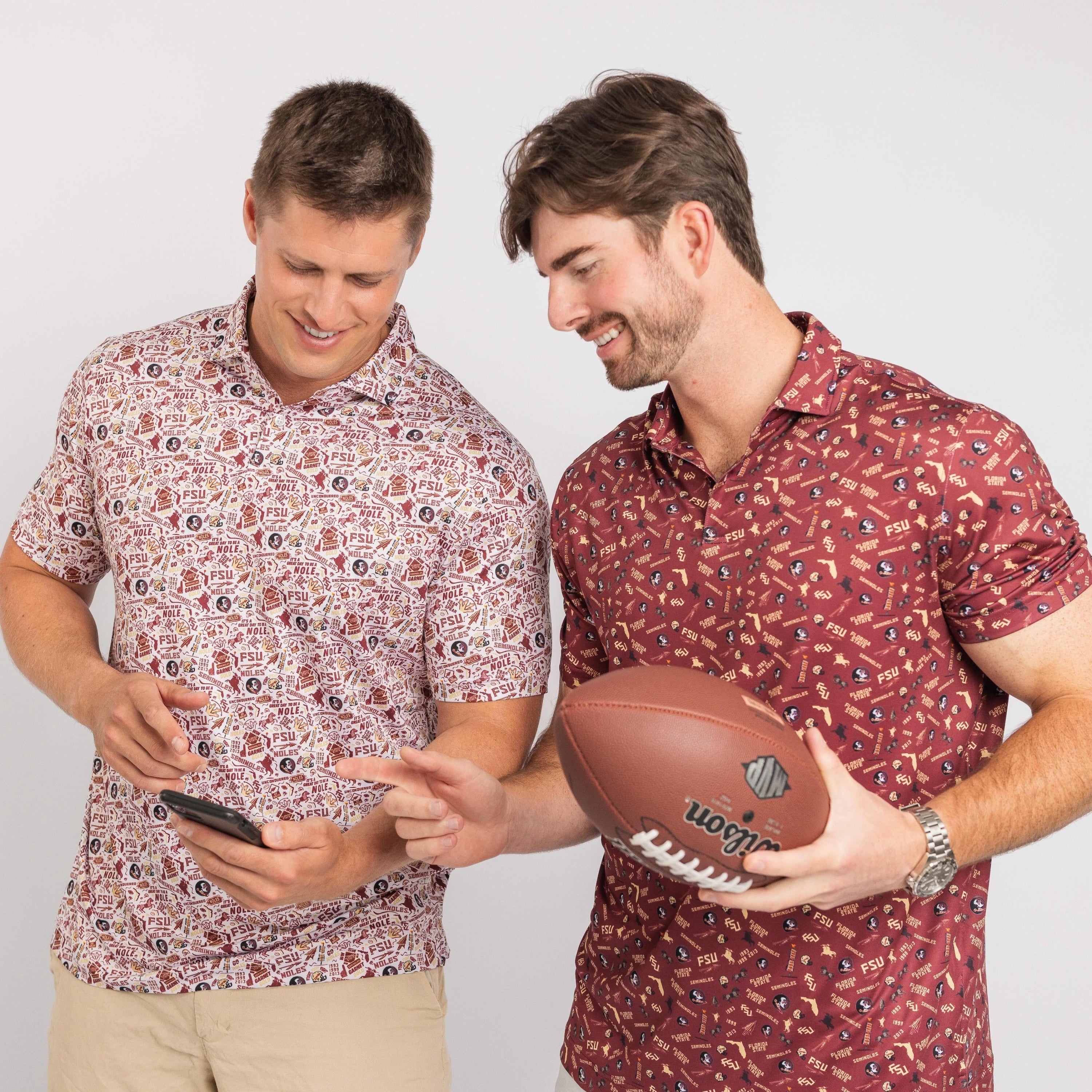 Two men wearing patterned shirts holding a football and a phone on a plain background