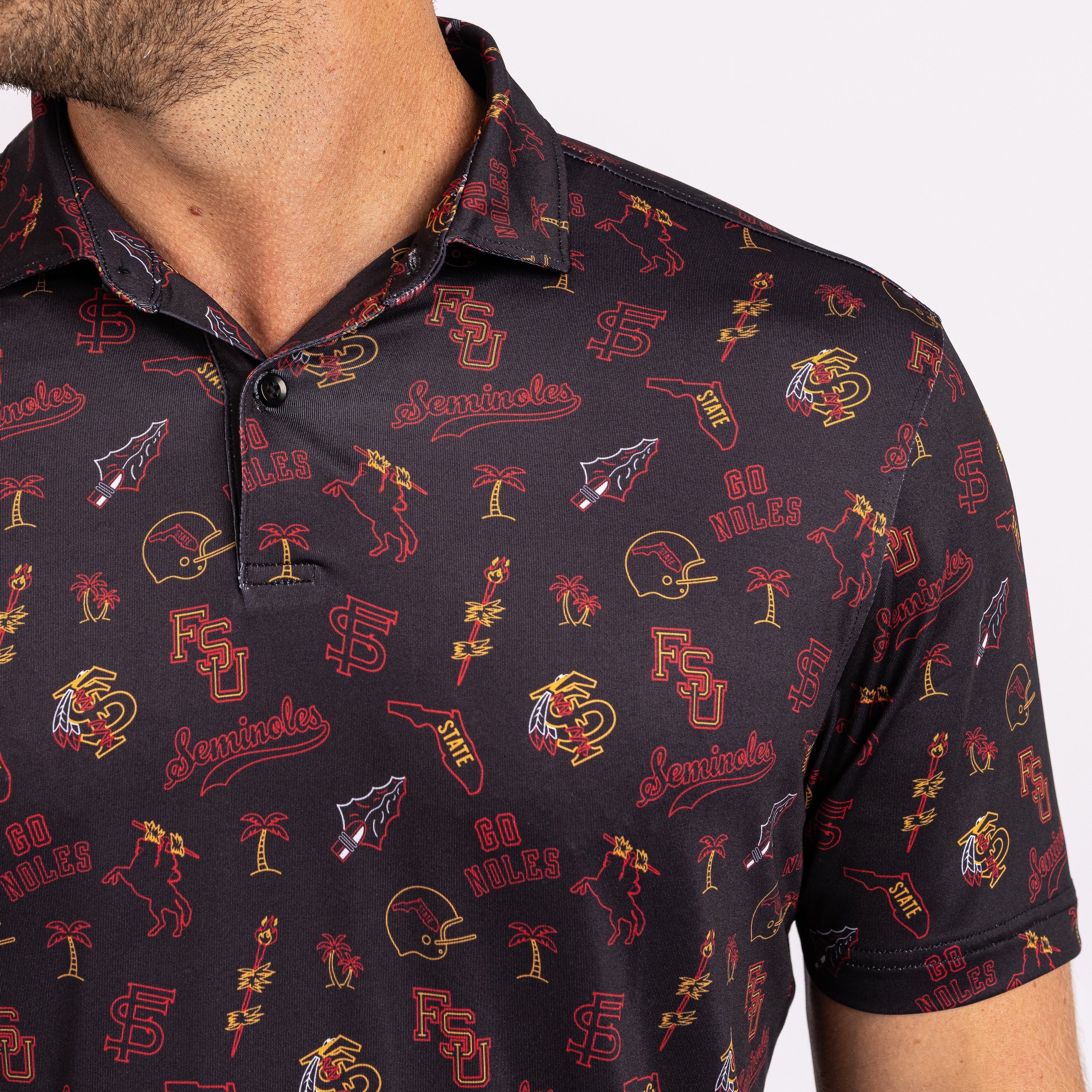 Close-up of a man wearing a dark polo shirt with an all-over Florida State University themed print featuring the FSU logo, horses, football helmets, and palm trees in red, gold, and white.