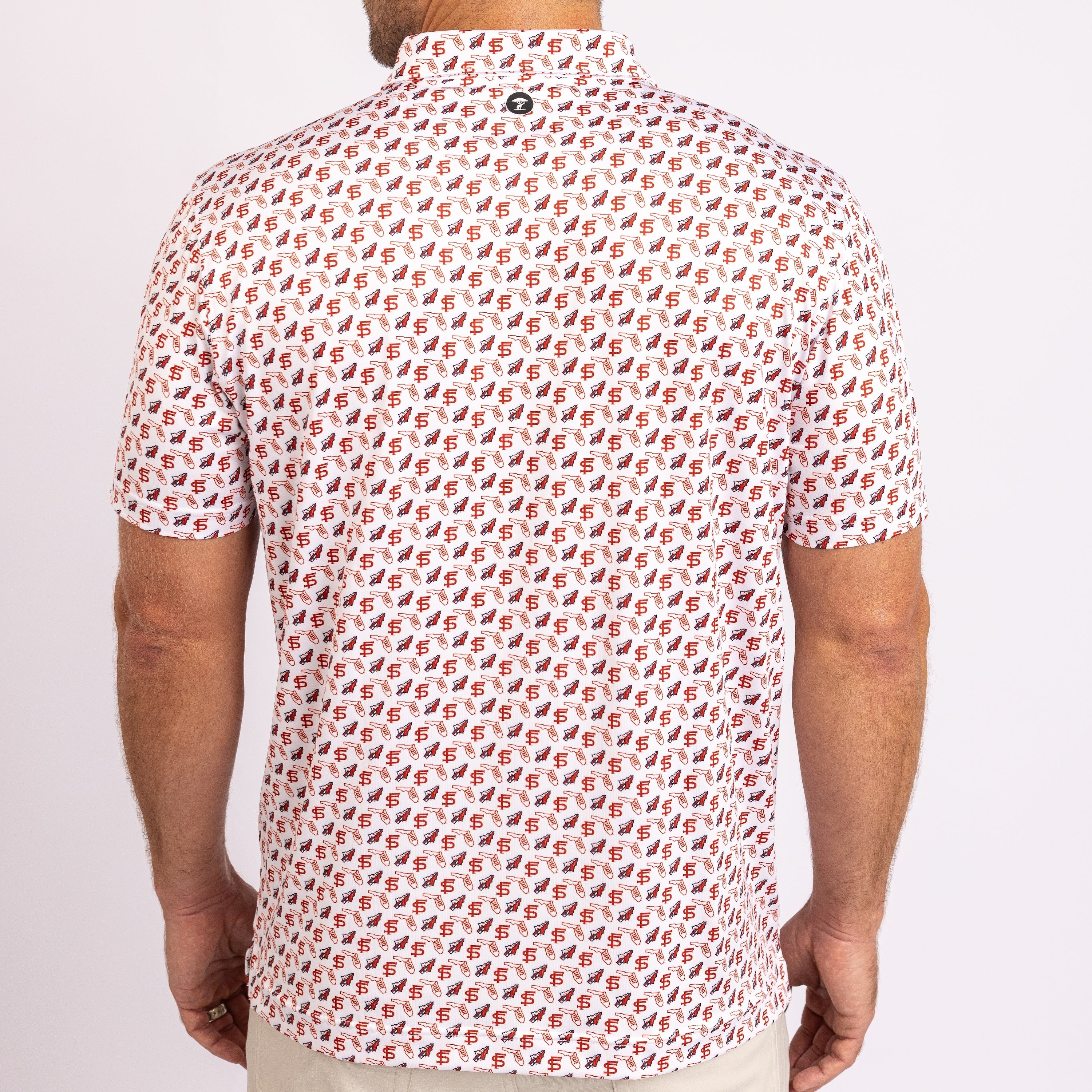 A man viewed from the back wearing a short-sleeve button-up shirt with an all-over repeating monogram pattern in red, black, and white.