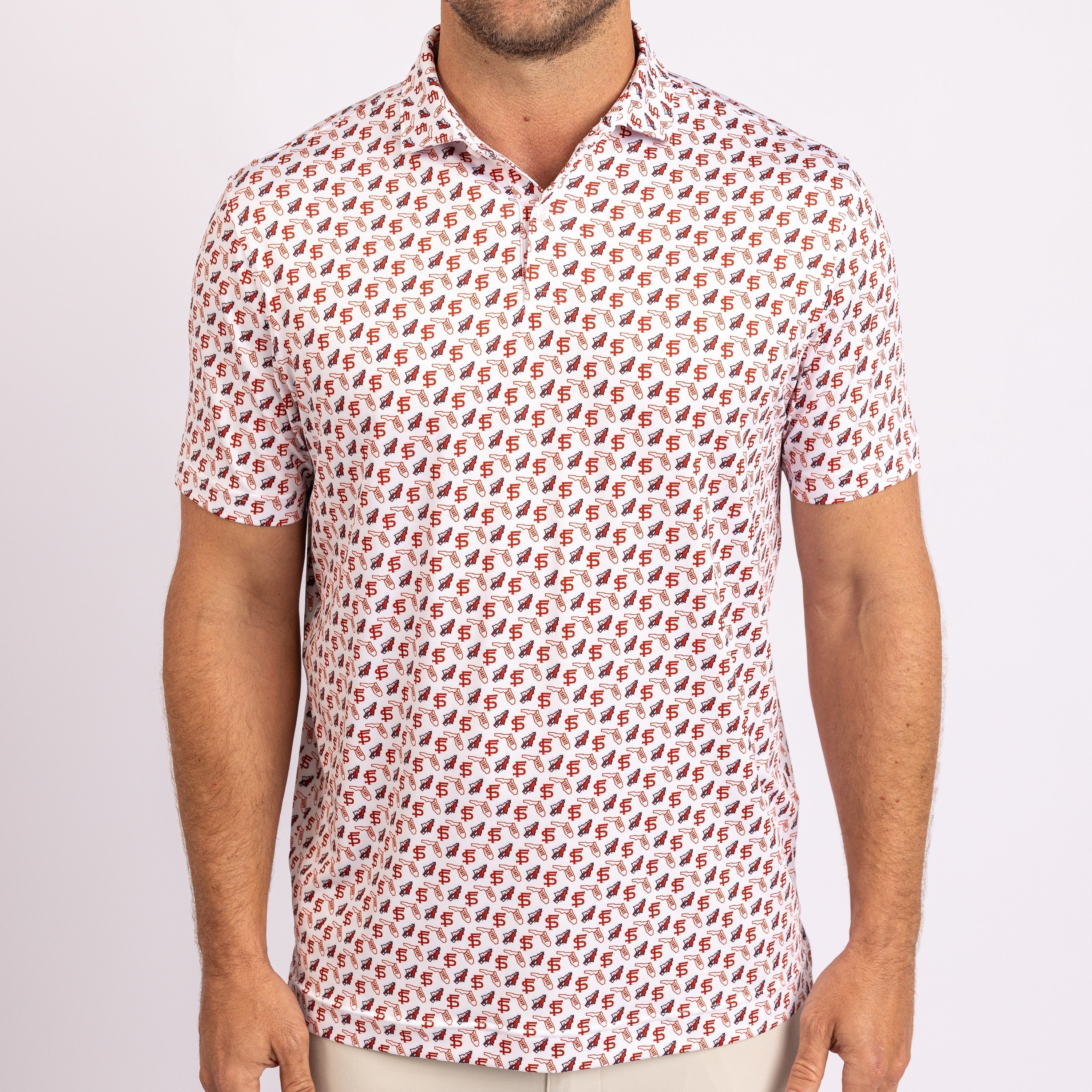 A man wearing a short-sleeve polo shirt with an all-over repeating monogram pattern of the letter 'F' in red and blue on a white base, paired with light beige pants against a light gray studio background.