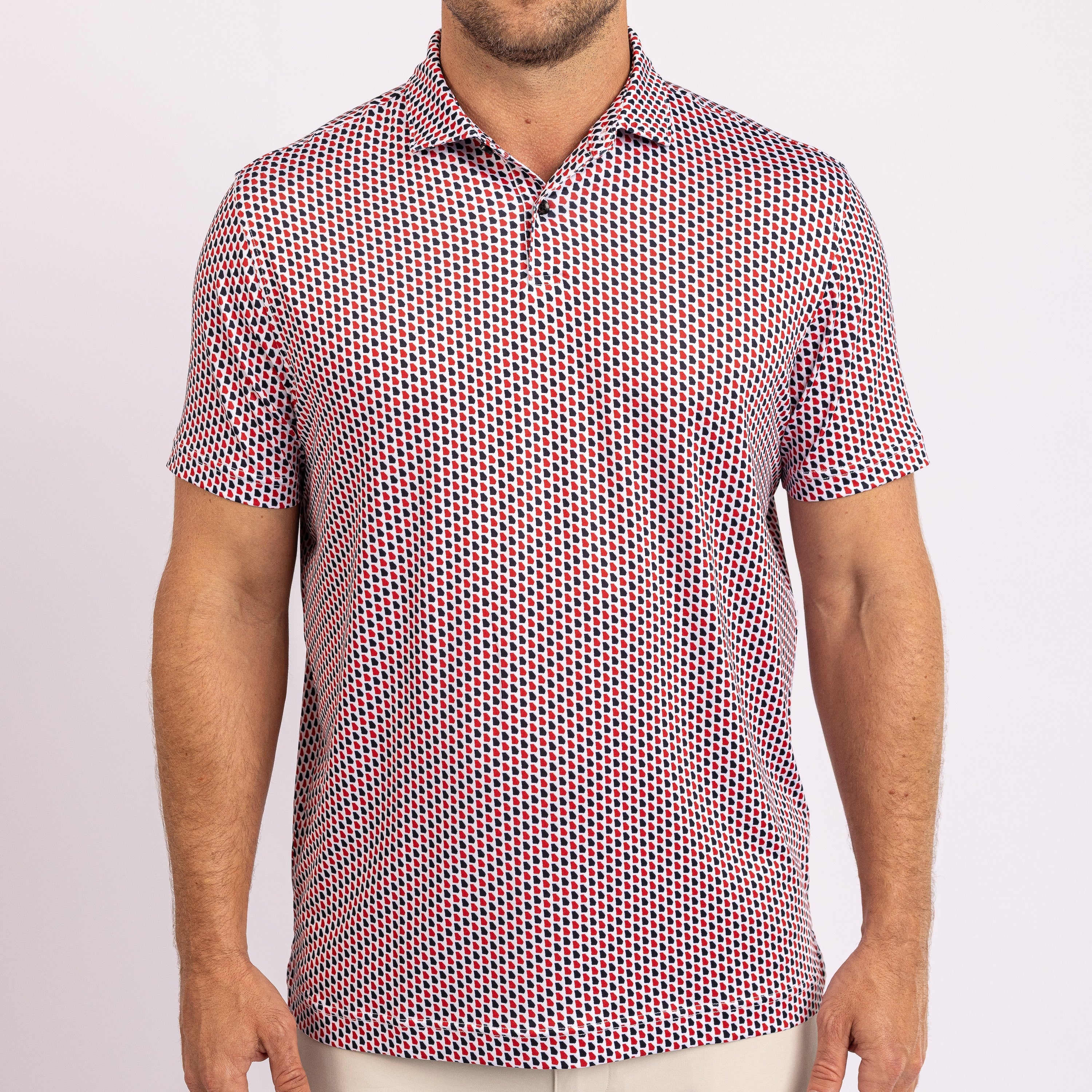 A man wearing a short-sleeve button-up shirt with a dense red, blue, and white geometric pattern