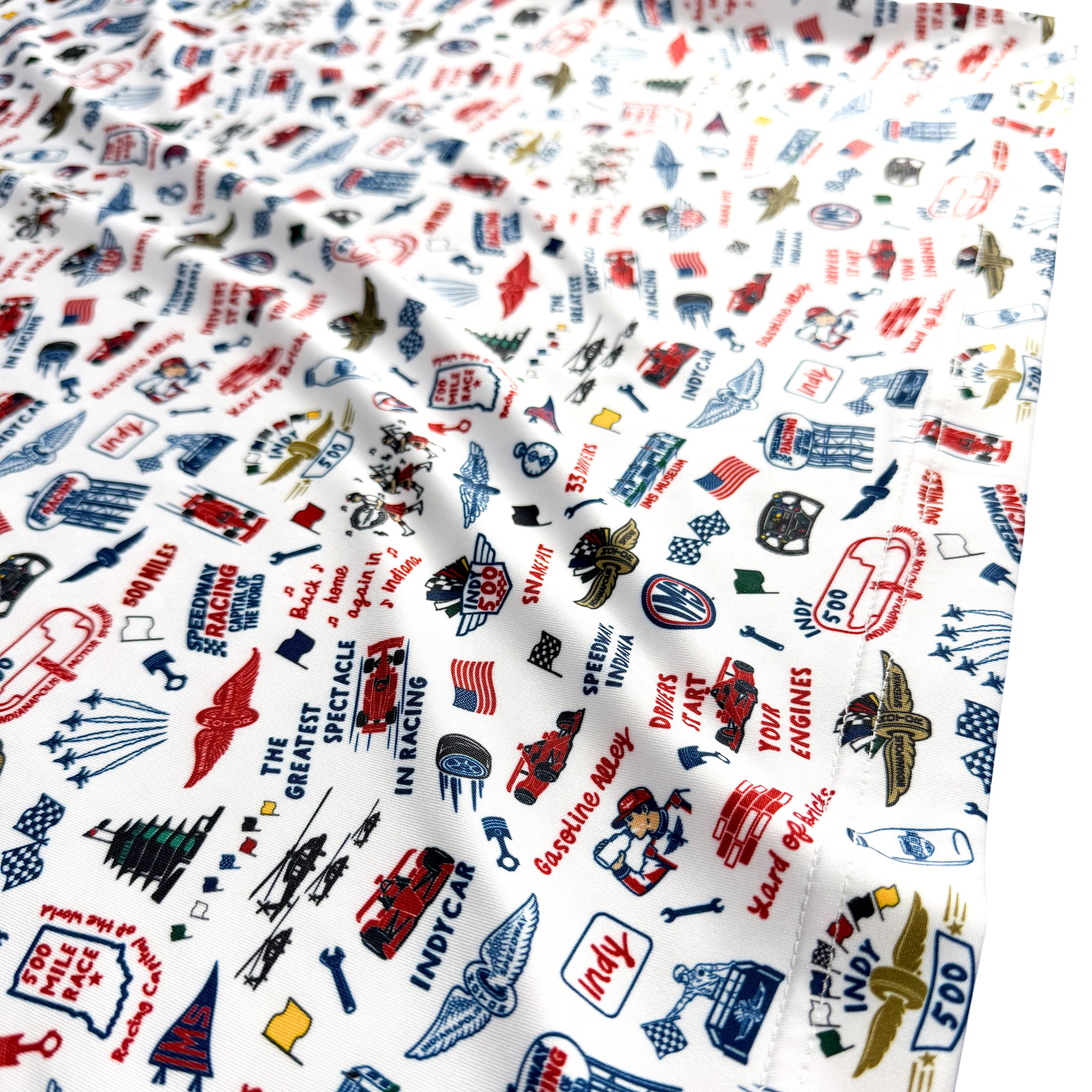 A close-up of a white fabric with an all-over printed pattern of vintage airplanes, flags, and signs in red, blue, black, and small yellow accents.