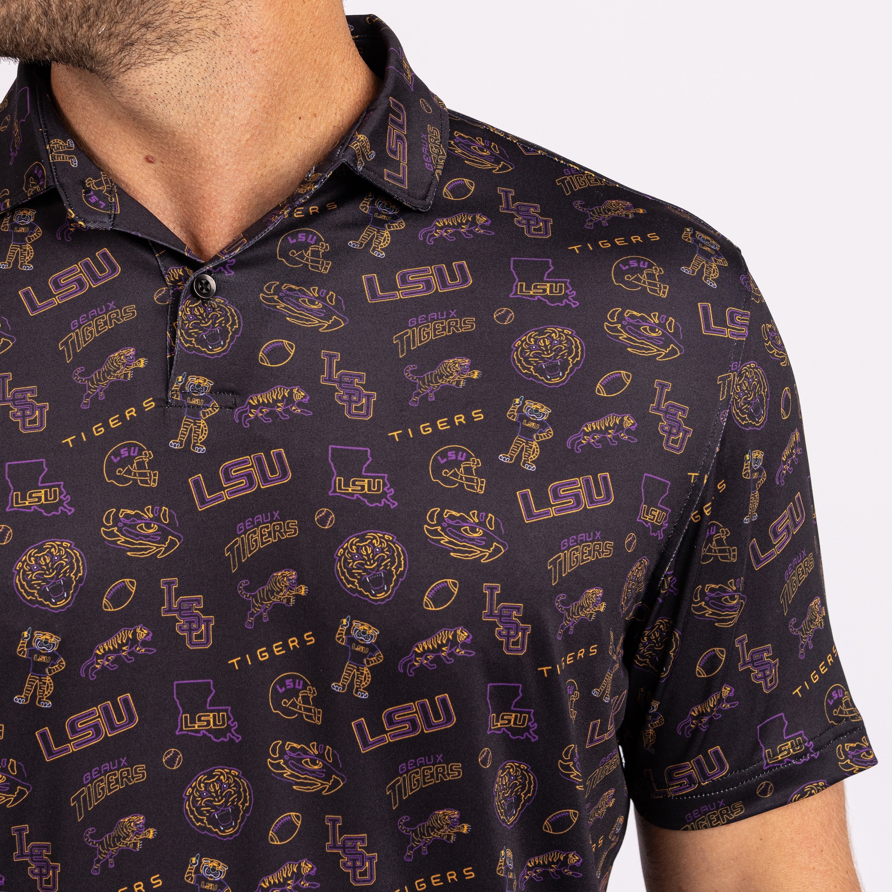 Close-up of a man wearing a short-sleeve polo shirt with an all-over LSU Tigers graphic print in purple and gold on a black background.