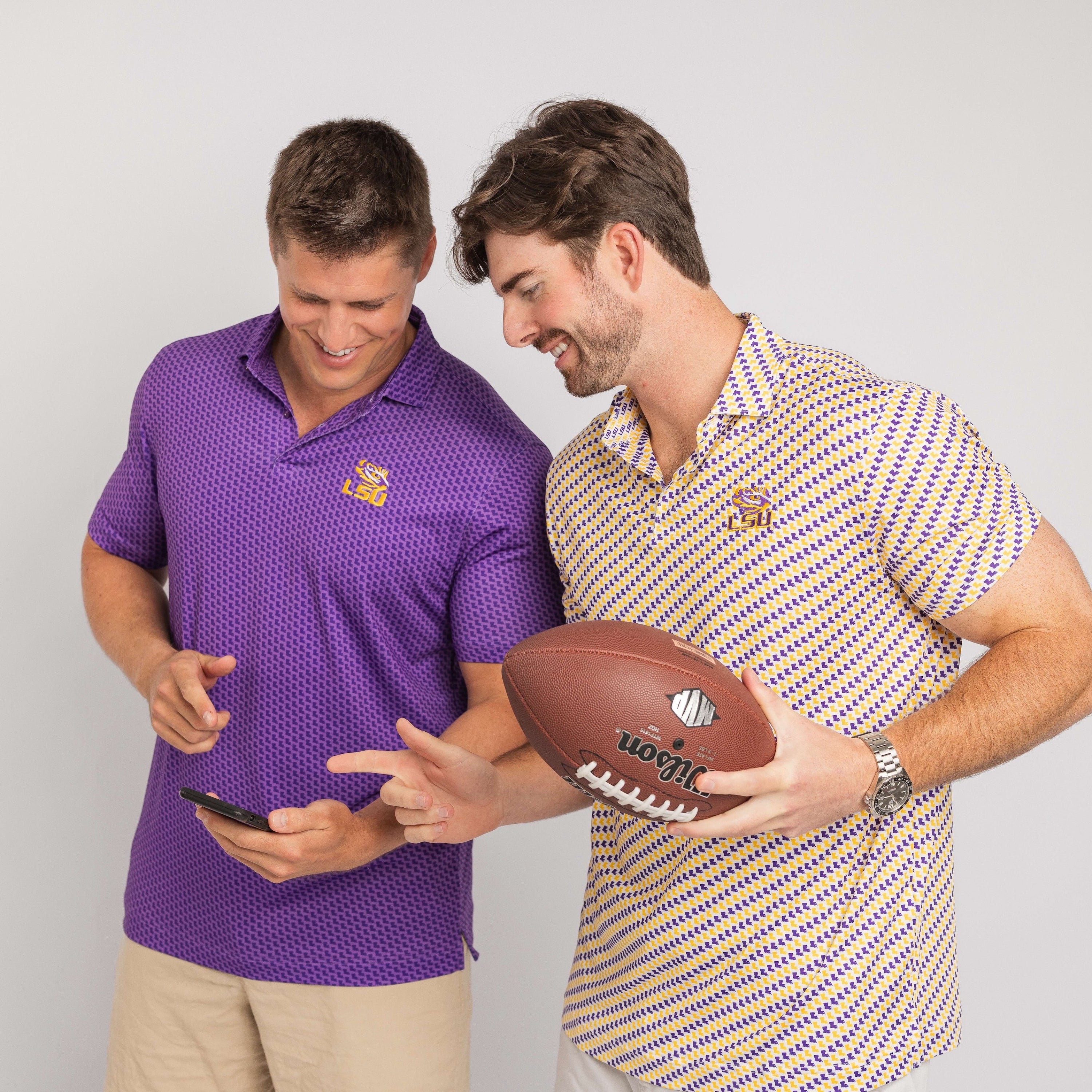 Two men, one in a purple shirt with a logo and the other in a patterned shirt holding a football, against a plain background.