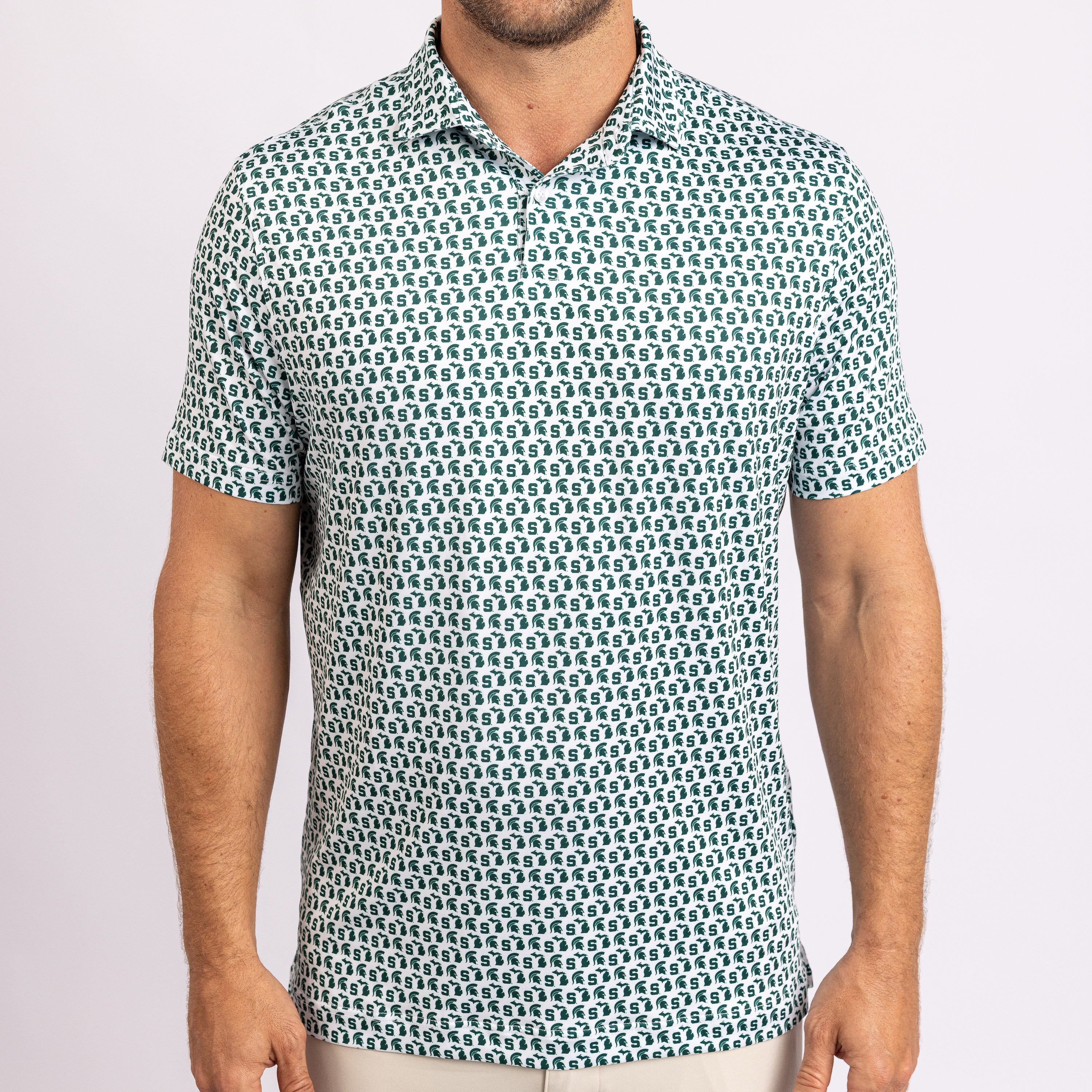 A man wearing a short-sleeve polo shirt with an all-over repeating geometric pattern in teal and white, shown from the chin down against a plain light background.