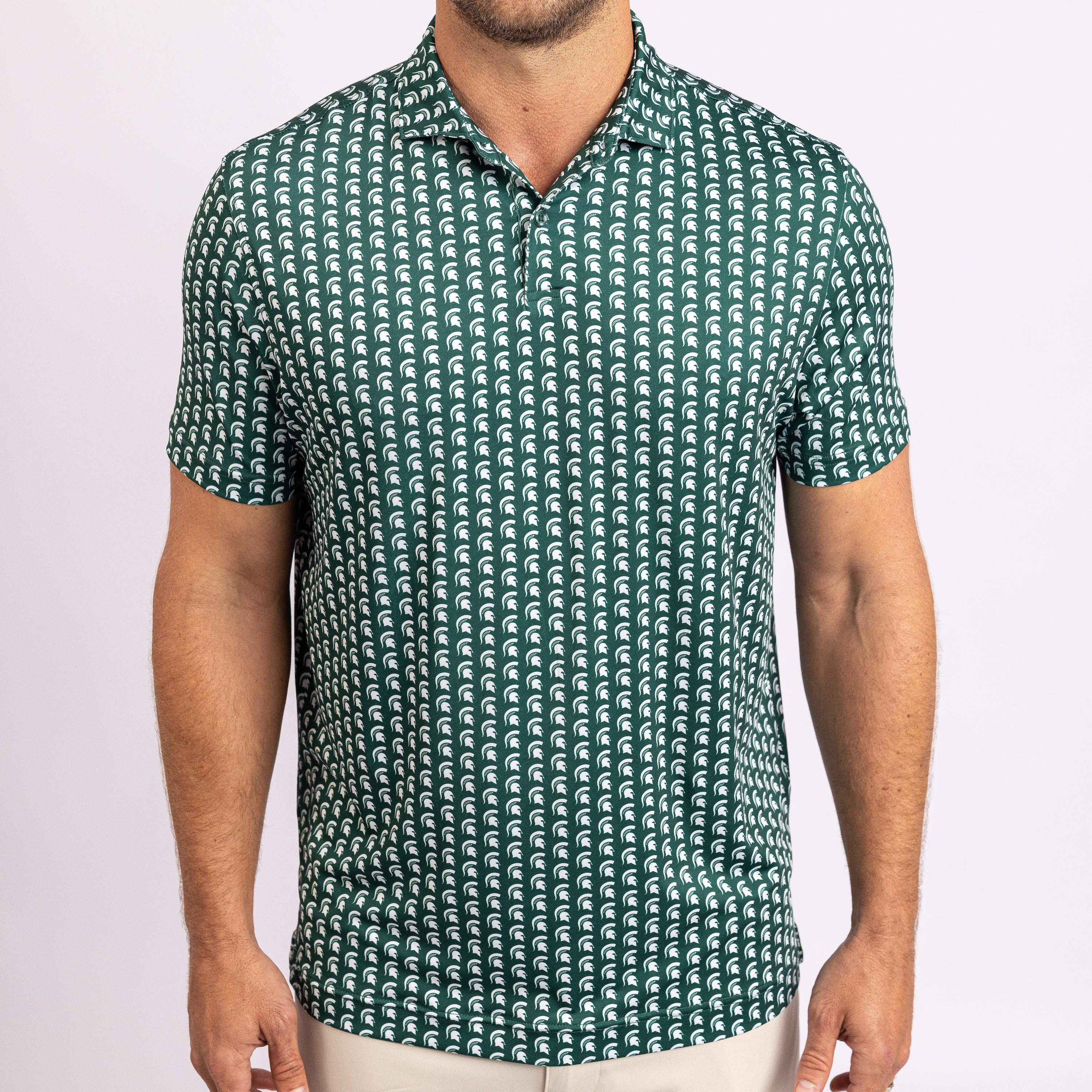 A man wearing a short-sleeve polo shirt with a repeating green and white wave pattern, shown from the neck down against a plain light background.