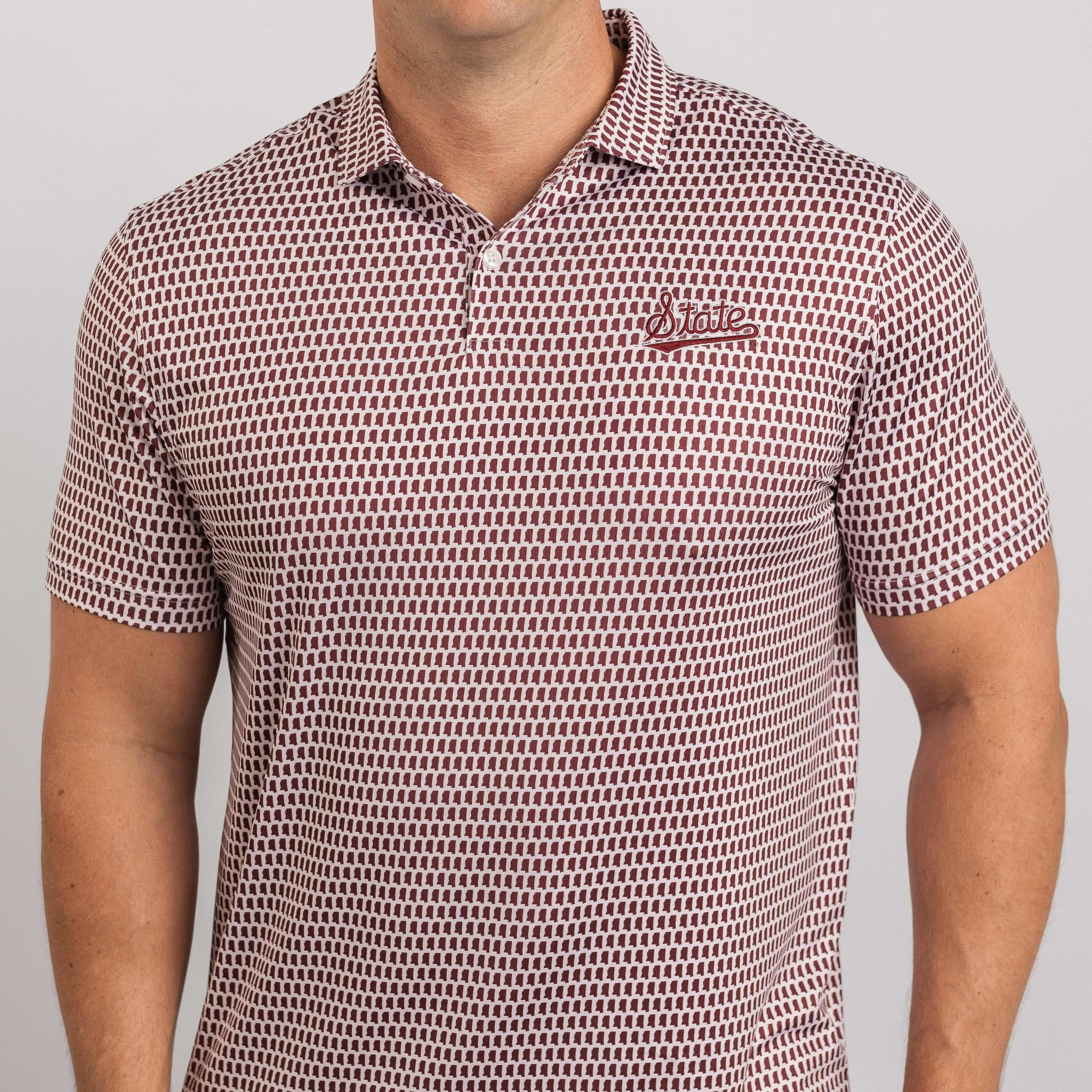 Man wearing a patterned polo shirt with a logo on a plain background