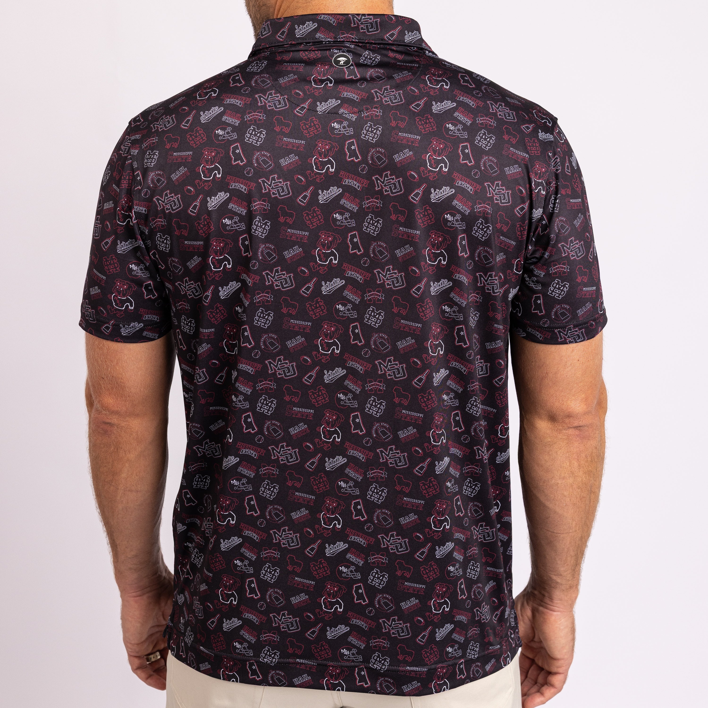 A man viewed from the back wearing a short-sleeve polo shirt with an all-over retro gaming controller pattern in dark red, gray, and white on a black base.