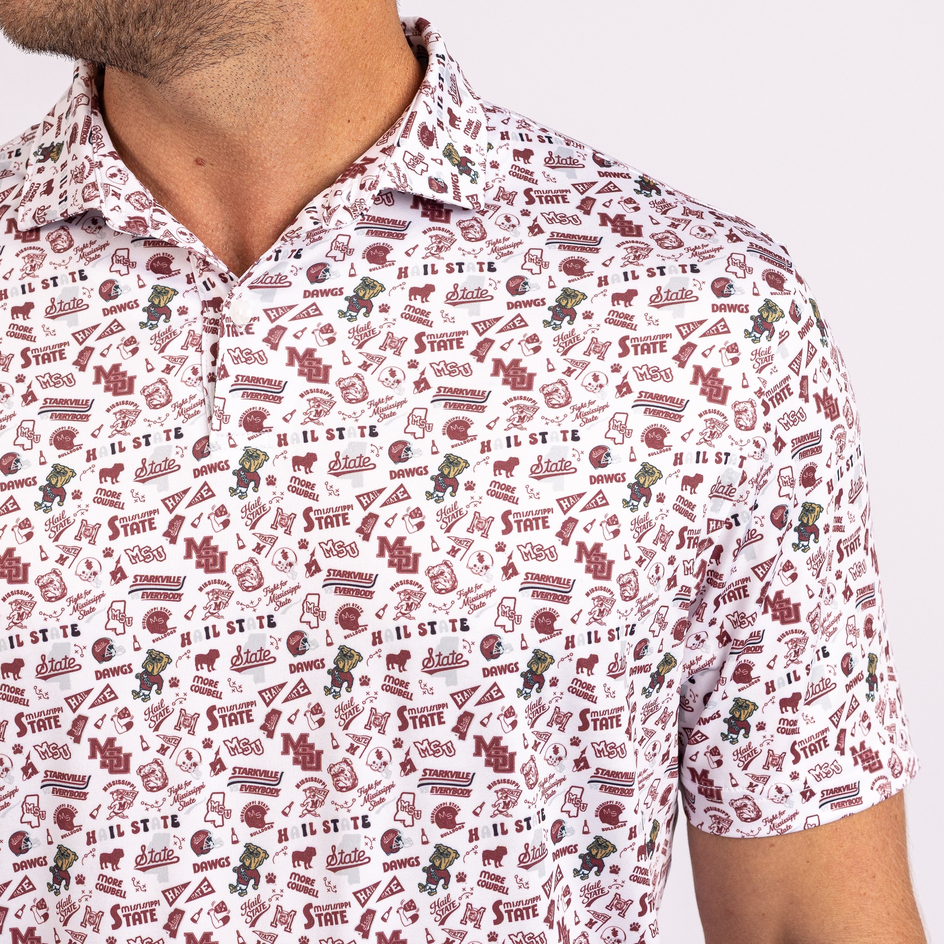 A close-up of a man wearing a short-sleeve polo shirt with an all-over maroon and green collegiate-style print on a white background. The shirt features repeated logos, text, and mascot graphics.
