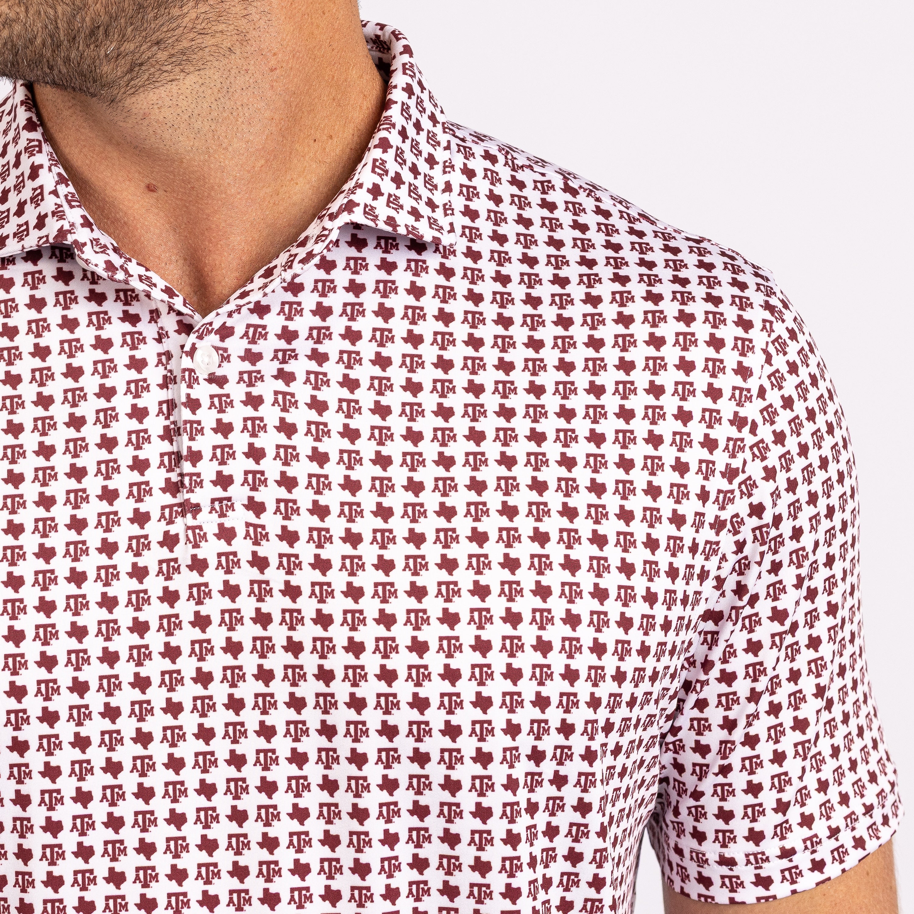 Close-up of a short-sleeve collared shirt with an all-over repeating monogram pattern in dark red on a white base, worn by a model.