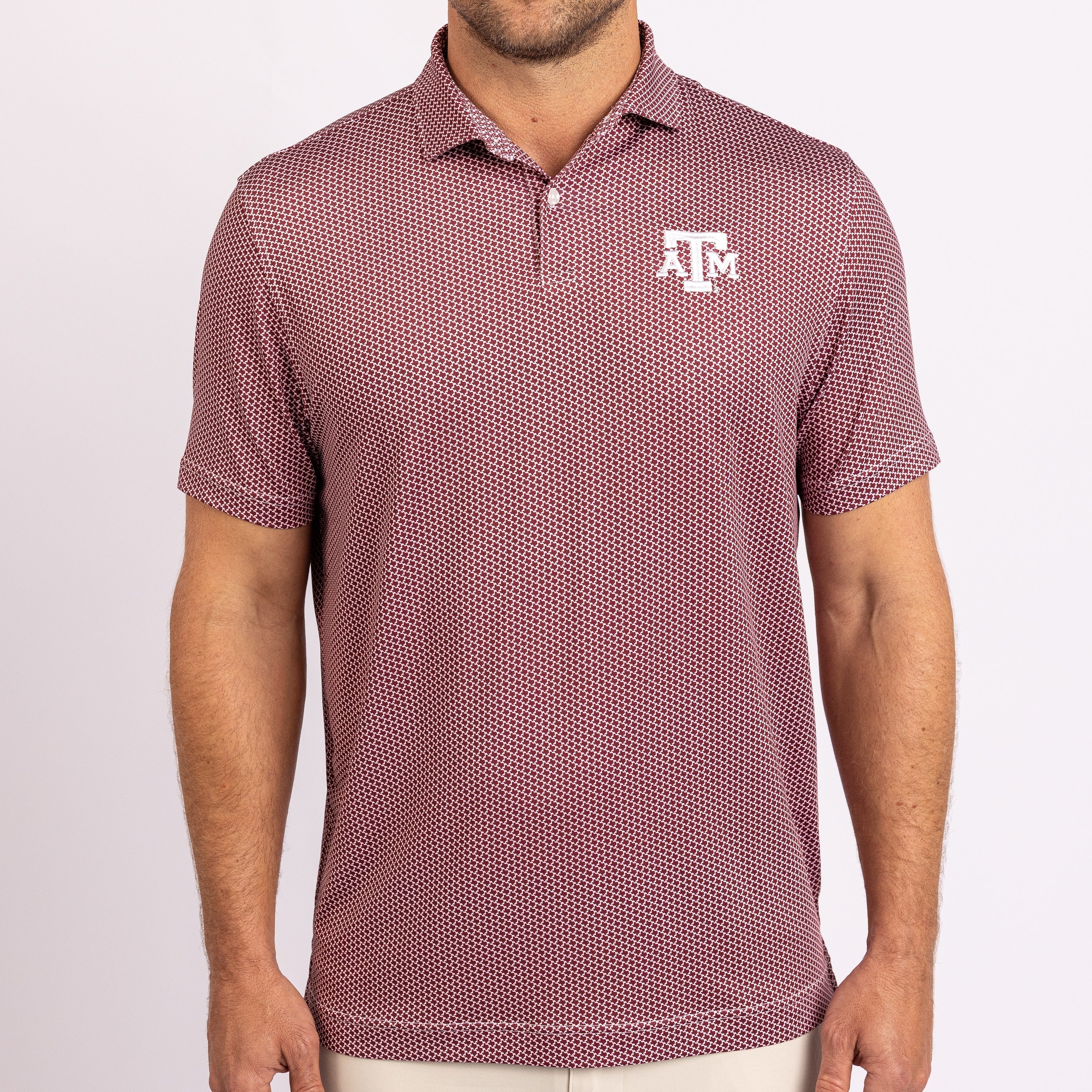A man wearing a short-sleeve polo shirt with a dense micro-dot pattern in dusty rose and white, featuring a white Texas A&M Aggies logo on the left chest.