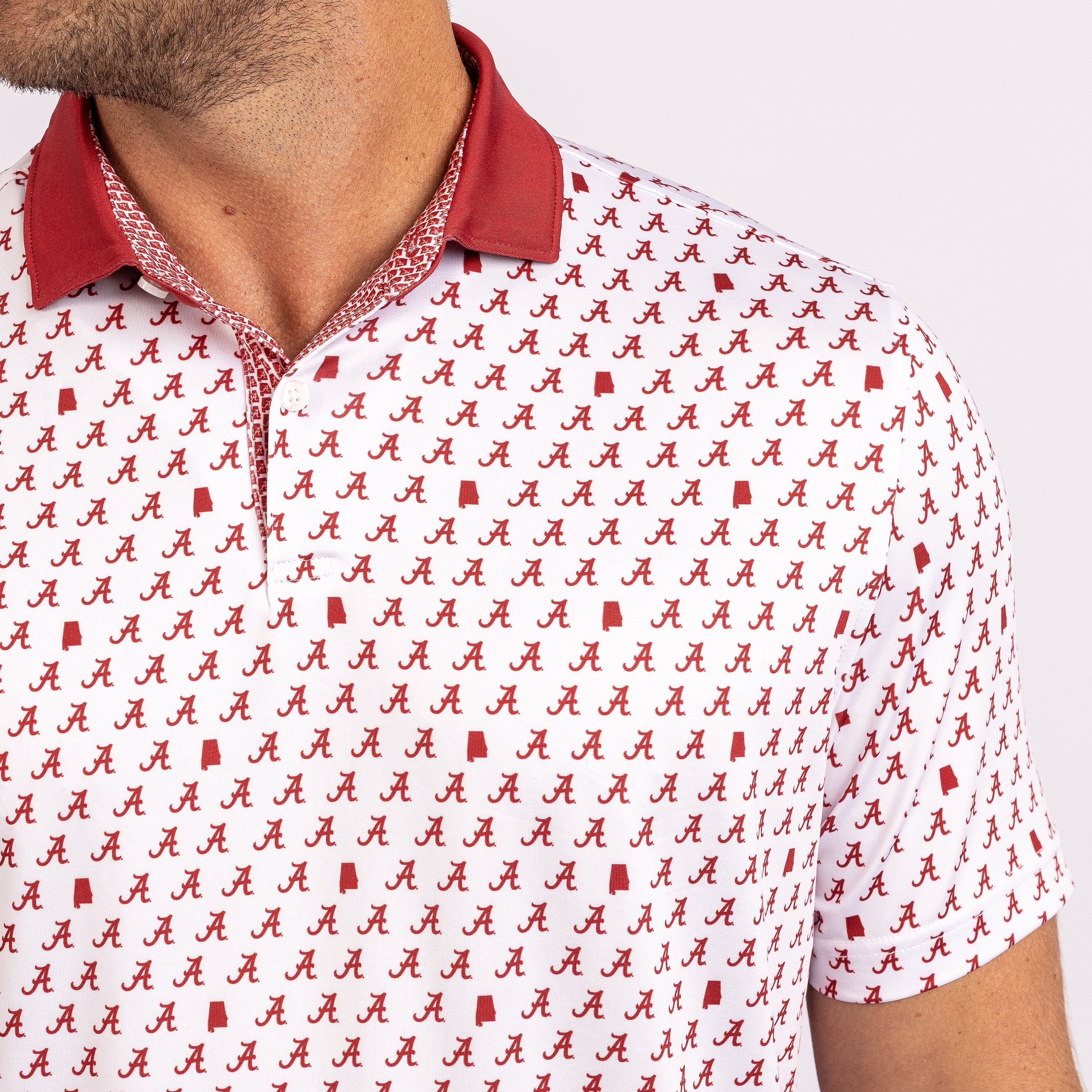 A close-up of a man wearing a white short-sleeve polo shirt with a red collar and an all-over repeating red script logo pattern.
