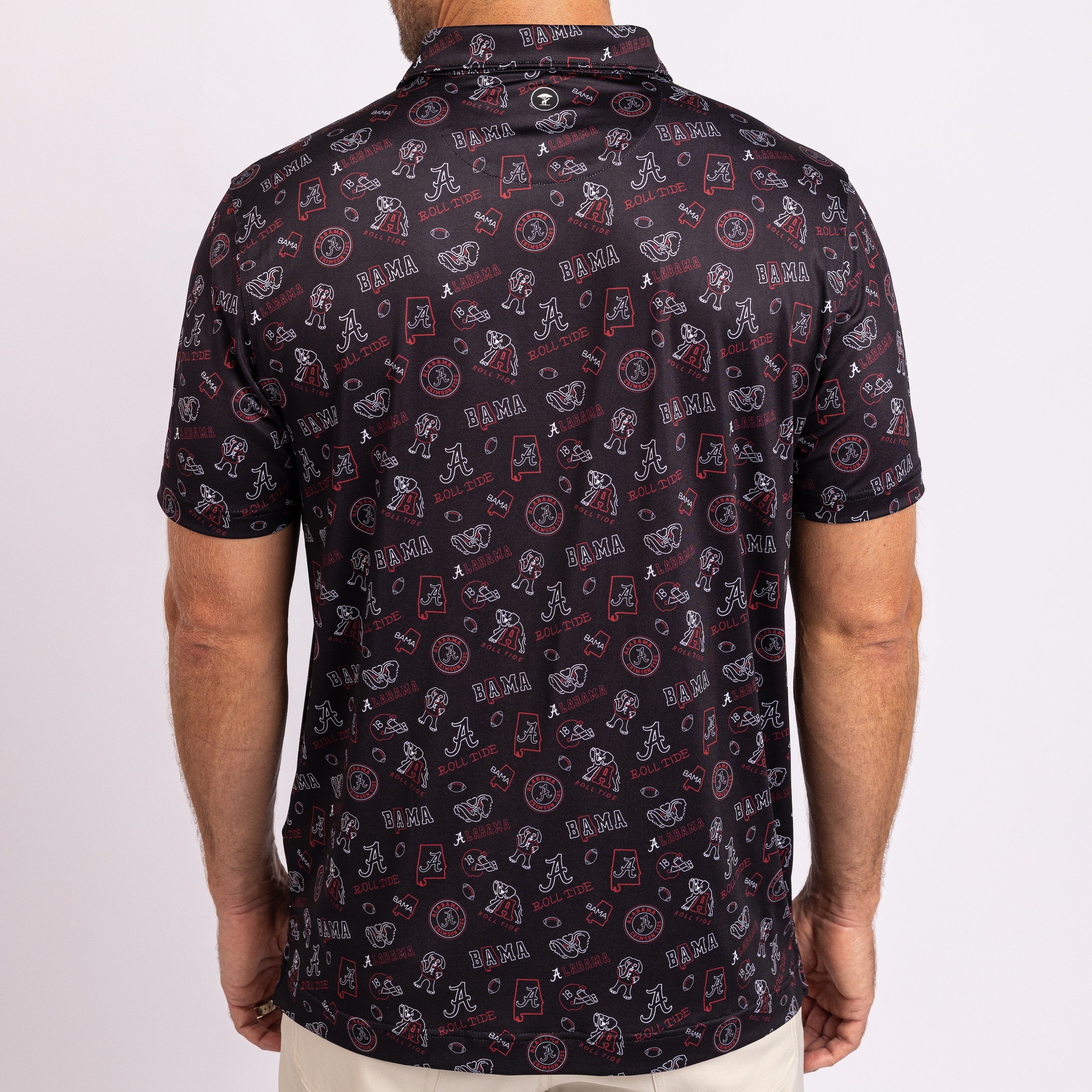 A man wearing a short-sleeve collared shirt from the back, featuring an all-over print of the Alabama Crimson Tide logo in red, white, and black.