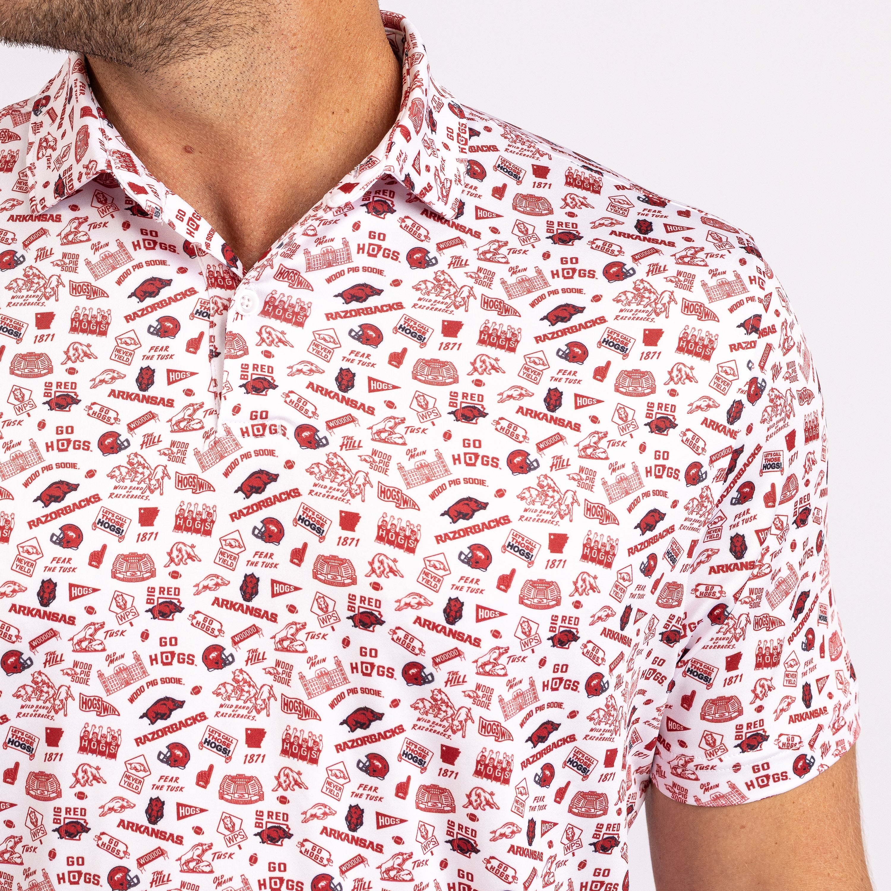 A close-up of a man wearing a white short-sleeve collared polo shirt with an all-over red Arkansas Razorbacks-themed graphic print.
