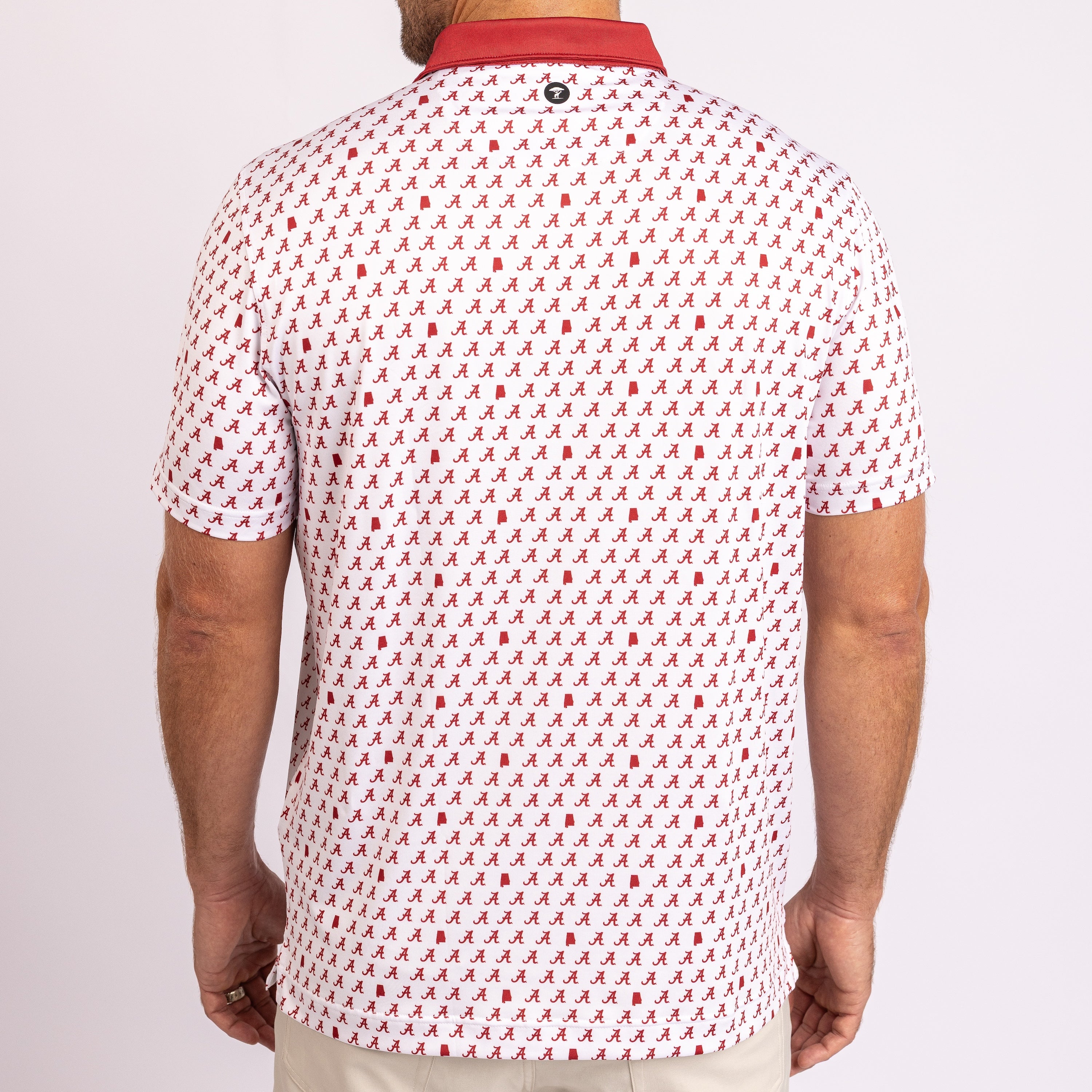 A man viewed from the back wearing a white short-sleeve polo shirt with a repeating red script pattern and a solid red collar.