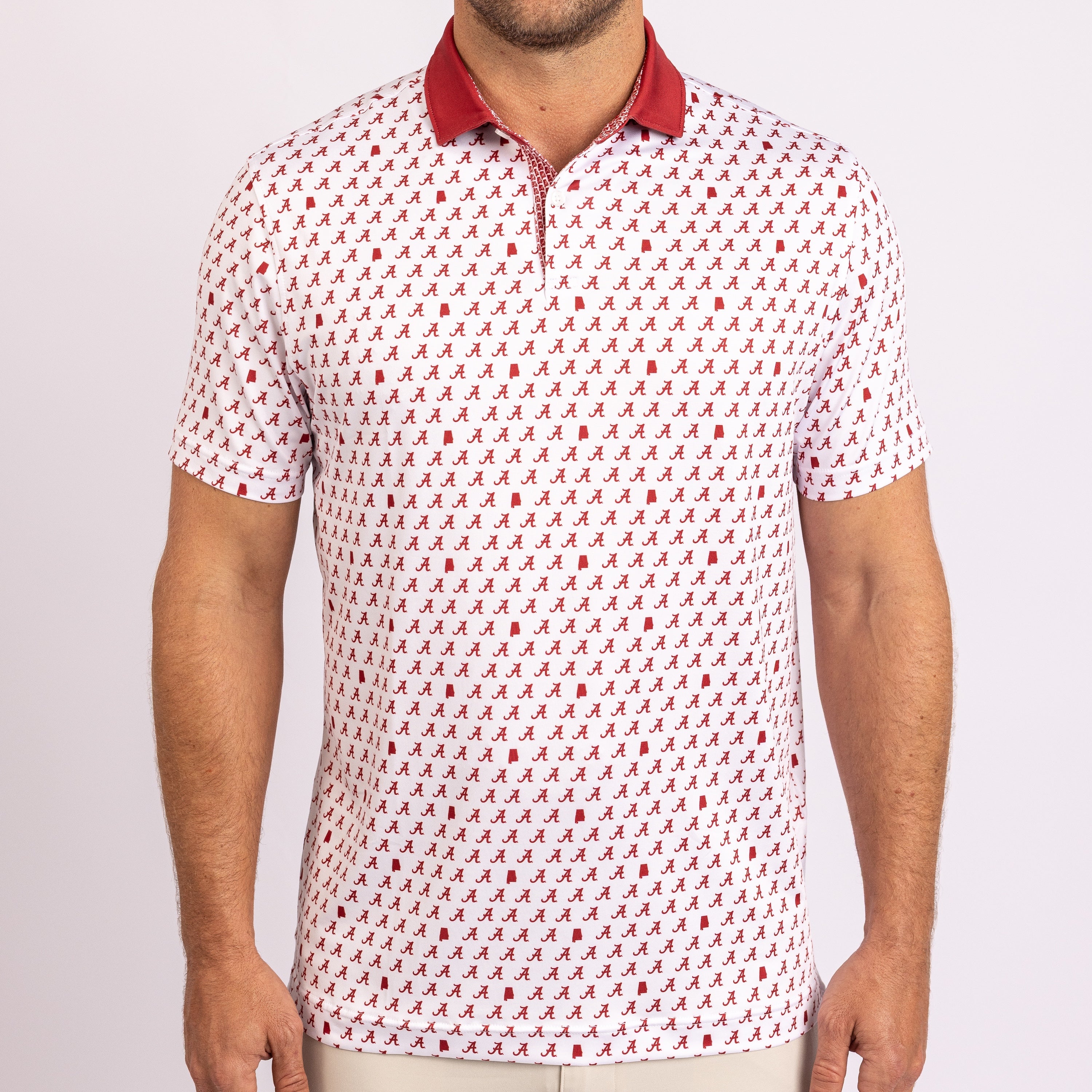A man wearing a short-sleeve polo shirt with a white base, an all-over small red pattern, and a solid red collar, shown against a light gray studio background.