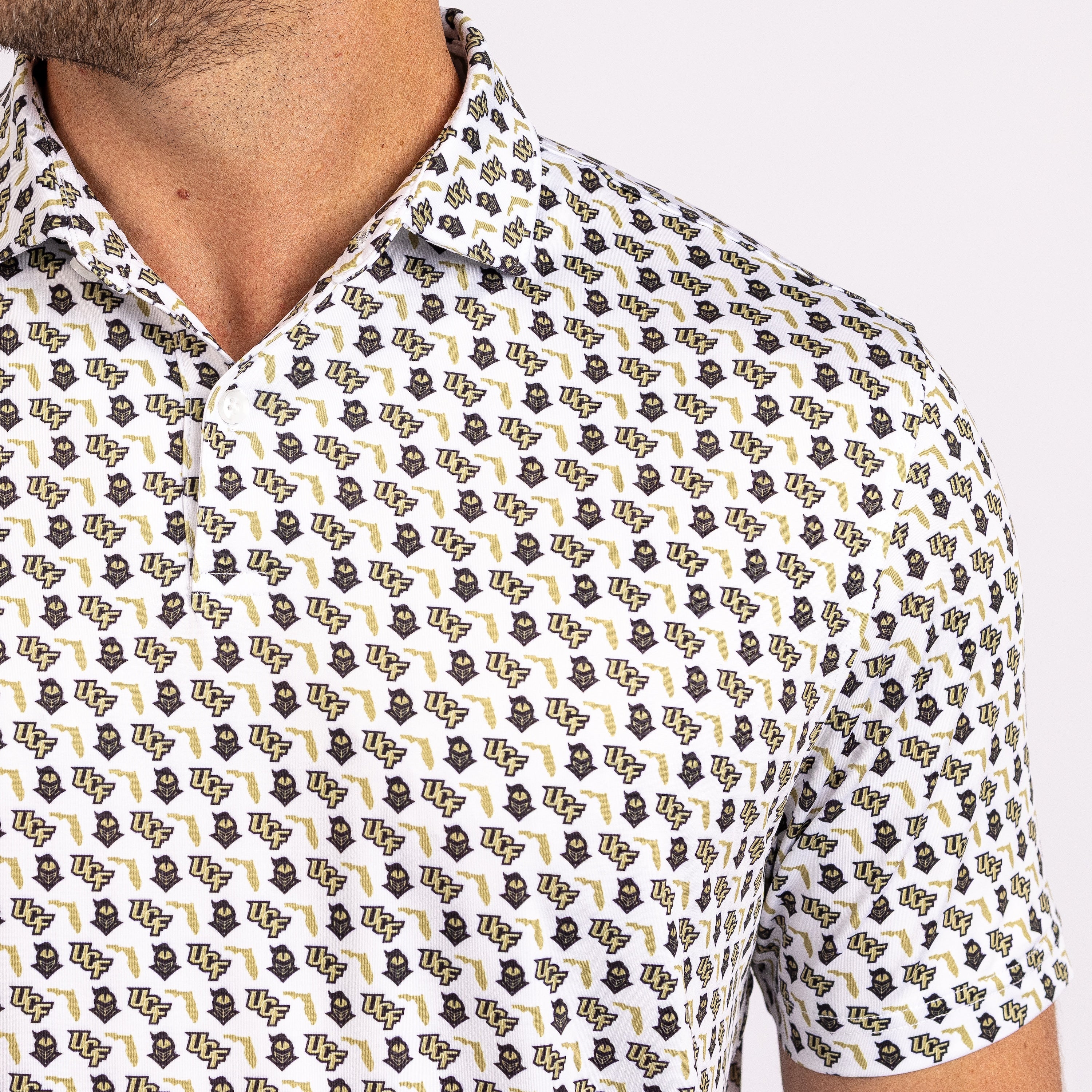 Close-up of a man wearing a short-sleeve collared shirt with an all-over repeating logo print in black, gold, and white.