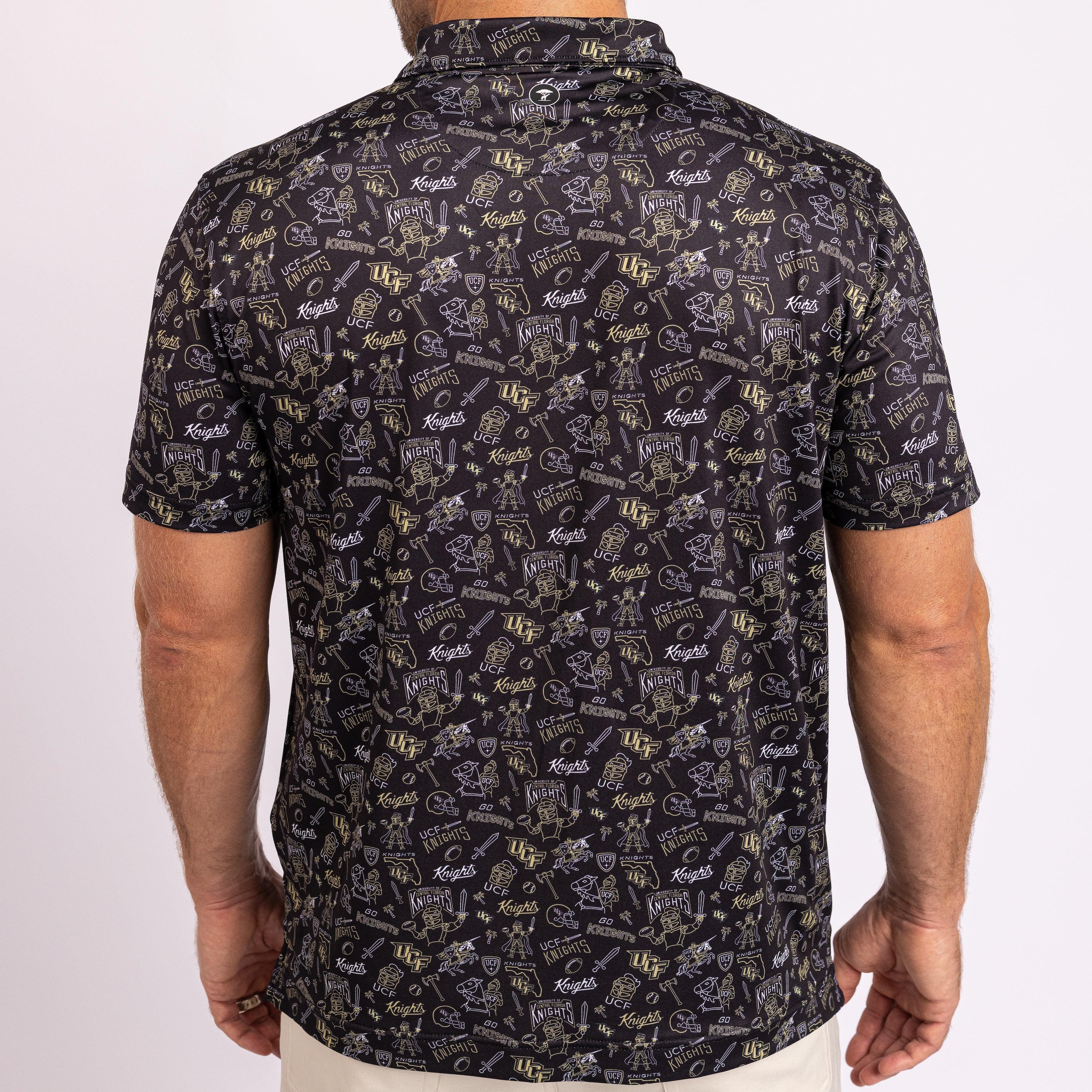 A man wearing a short-sleeve button-up shirt from the back, featuring a dark charcoal/black base with an all-over repeating pattern of gold and white golf club illustrations and the word 'Knights'.