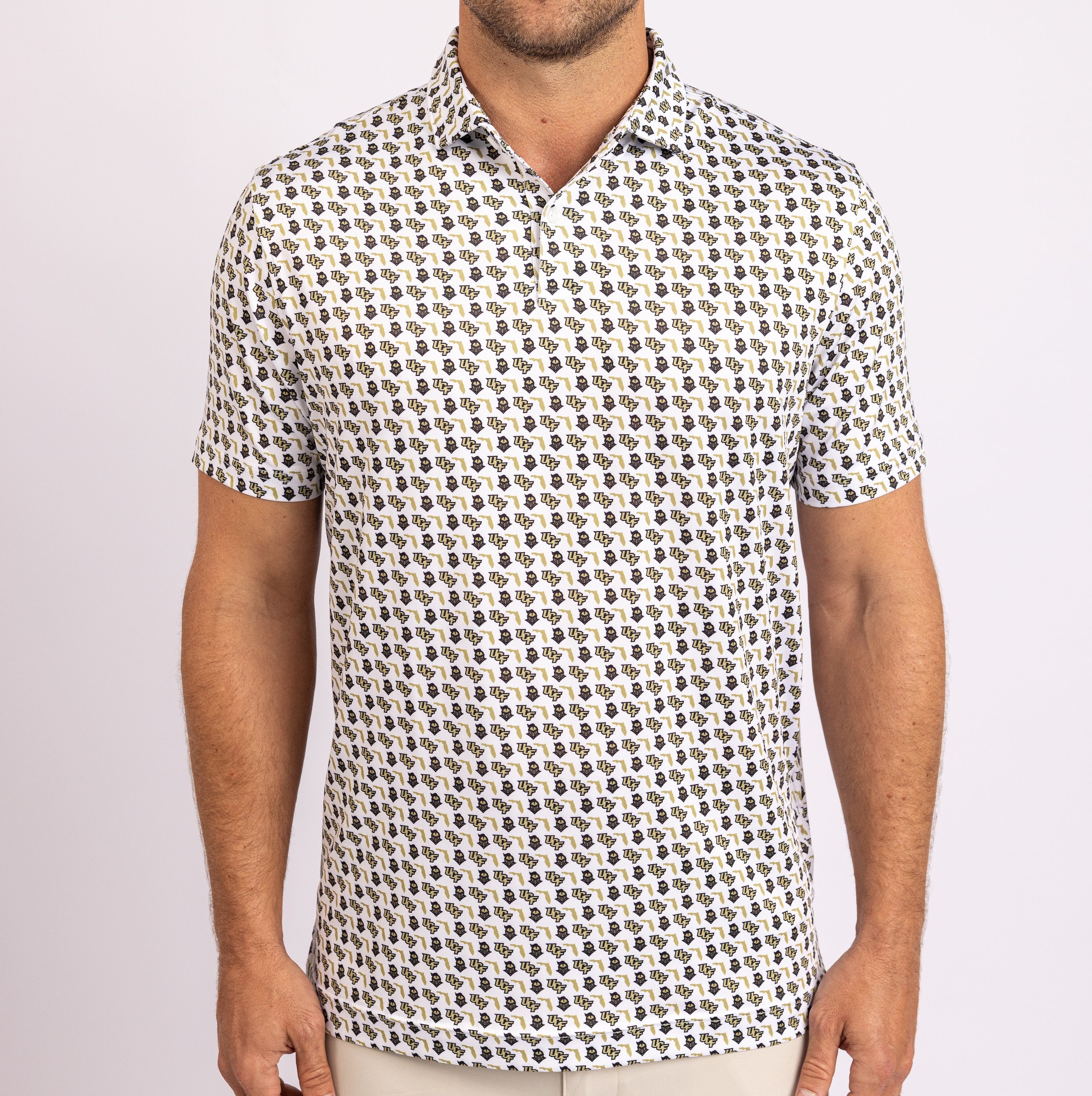 A man wearing a short-sleeve polo shirt with a dense, repeating black and brown paisley pattern on a white base, shown from the neck down against a light gray studio background.