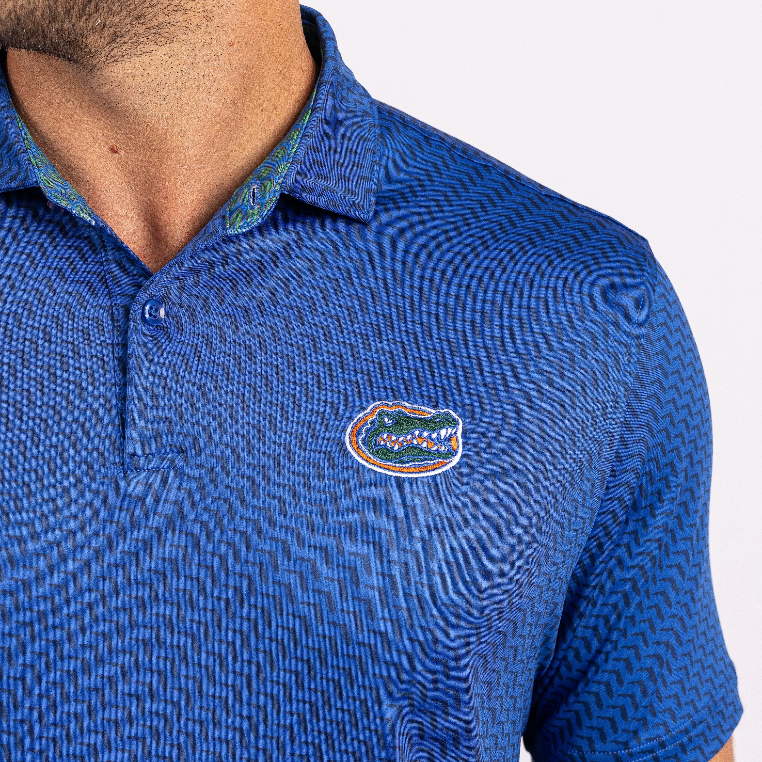 A close-up of a man wearing a blue patterned polo shirt with the Florida Gators logo on the chest, set against a plain white background.