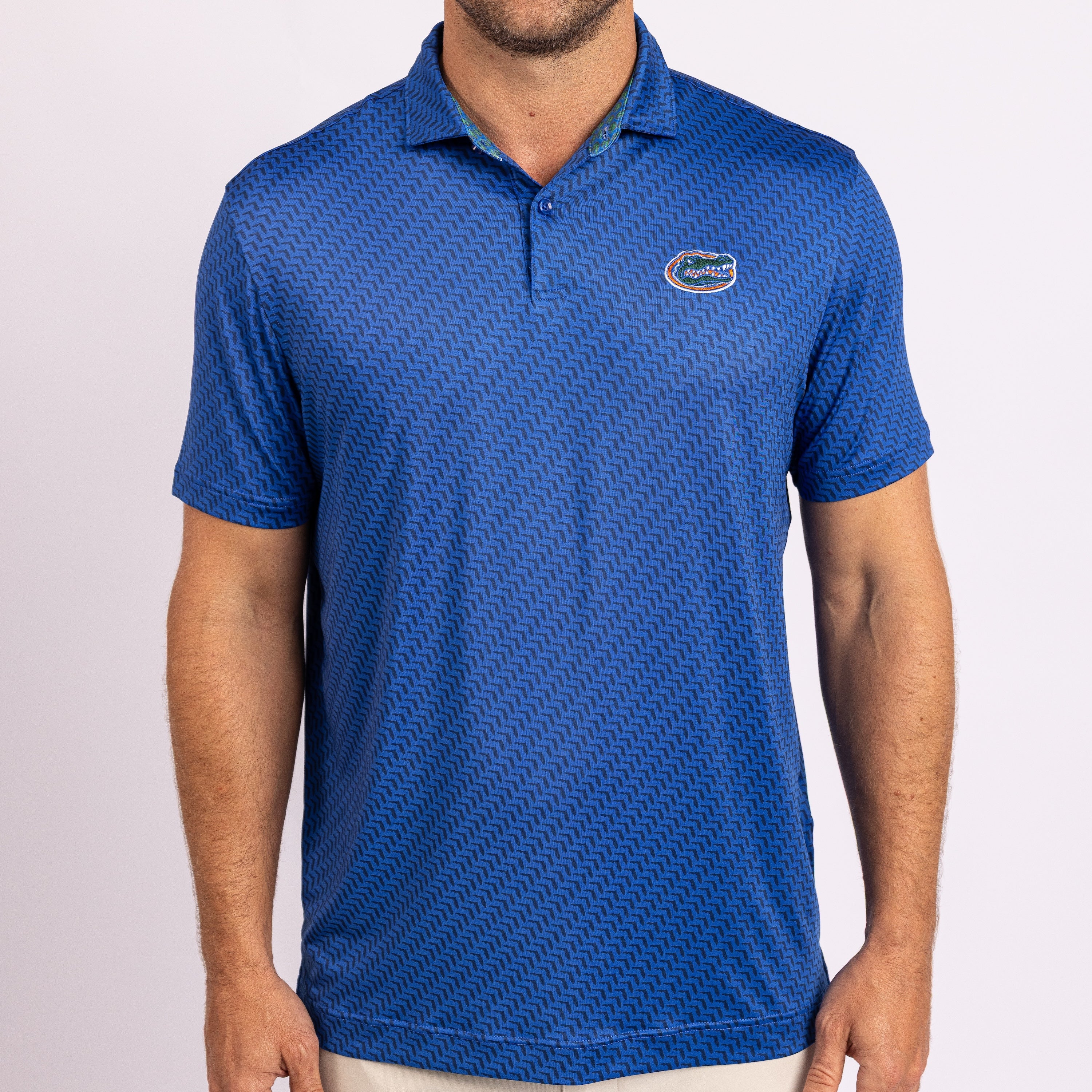 A man wearing a blue short-sleeve polo shirt with a pattern and the Florida Gators logo on the left chest, photographed against a light gray studio background.