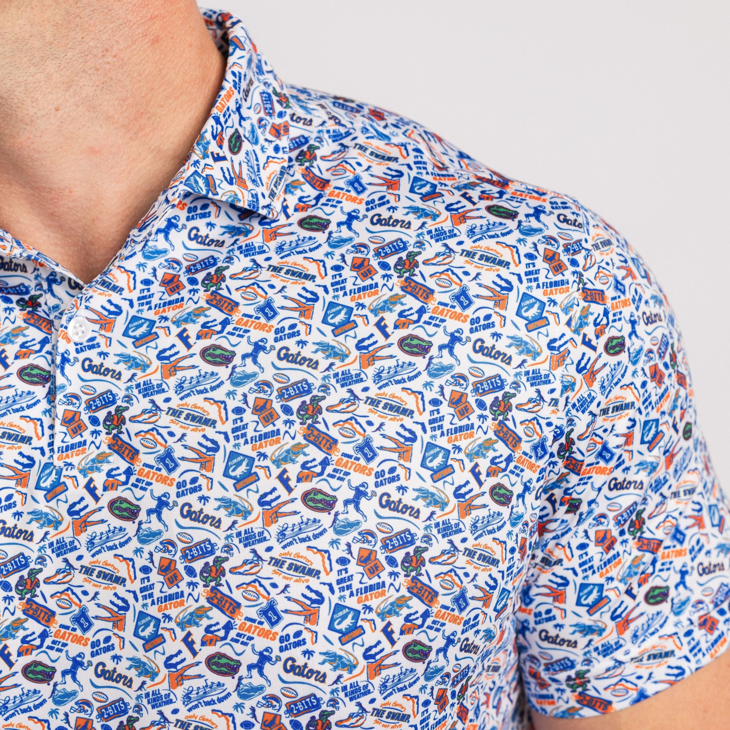 Close-up of a person wearing a patterned shirt with various logos and text.