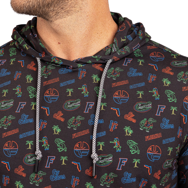 Close-up of a person wearing a dark charcoal hoodie with an all-over Florida Gators graphic print in green, orange, and blue, featuring white drawstrings.