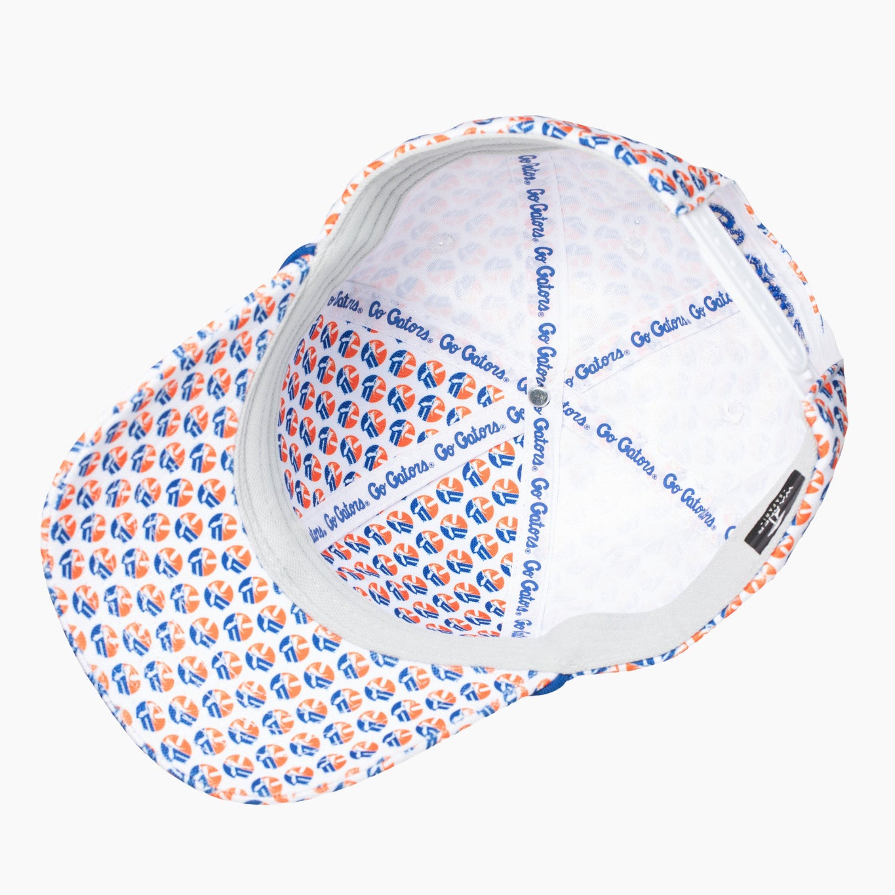 A white baseball cap with a repeating blue and orange logo pattern on the brim and crown, shown from an overhead angle on a light gray background.