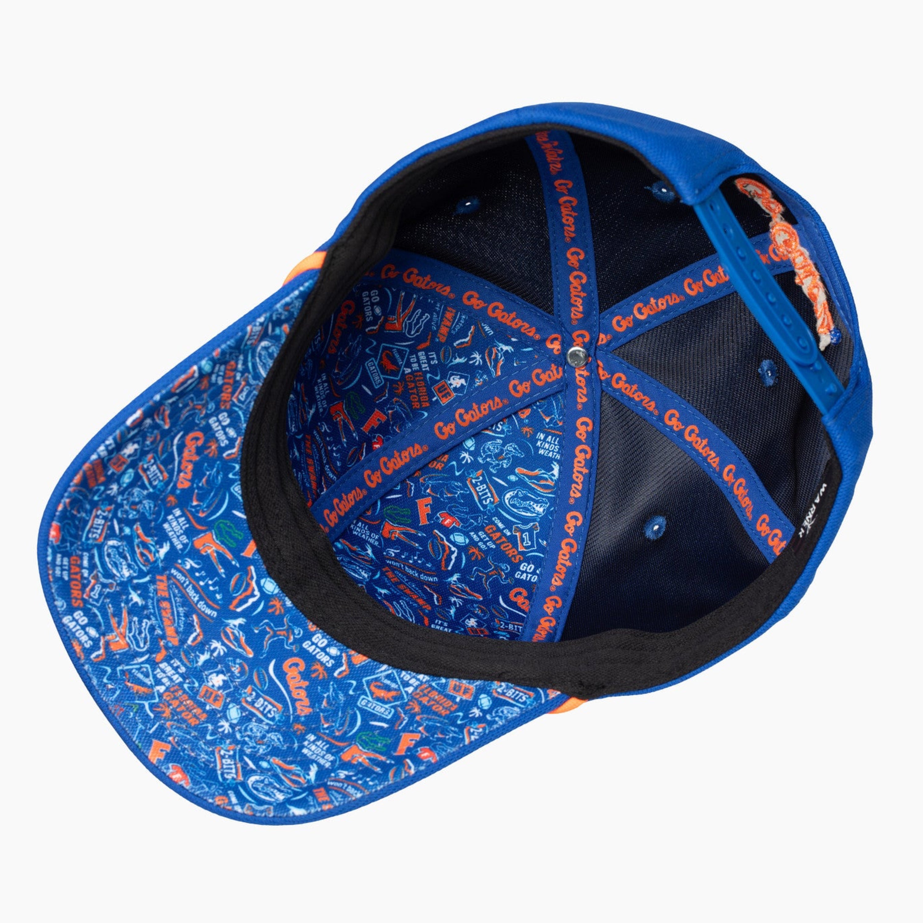 A blue baseball cap shown from an overhead angle, featuring an orange and blue patterned visor and orange embroidered details on the inner crown and side, photographed against a solid white background.