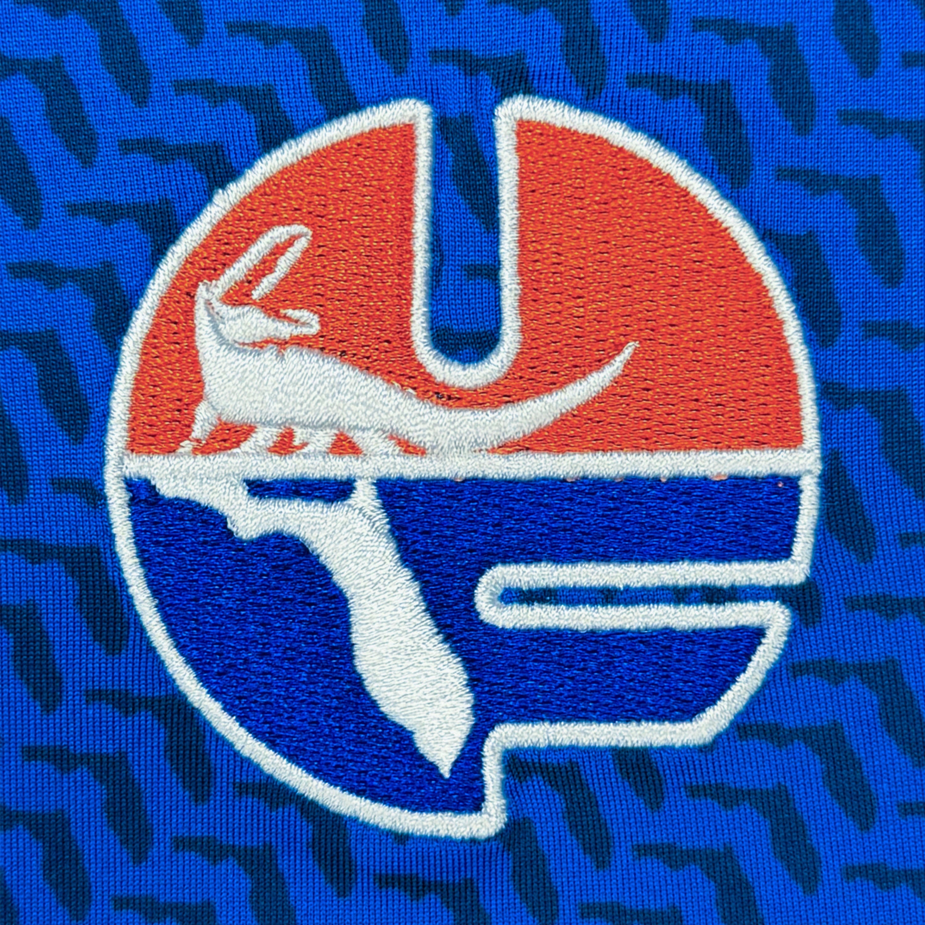 Embroidered logo with a gator design on a blue background