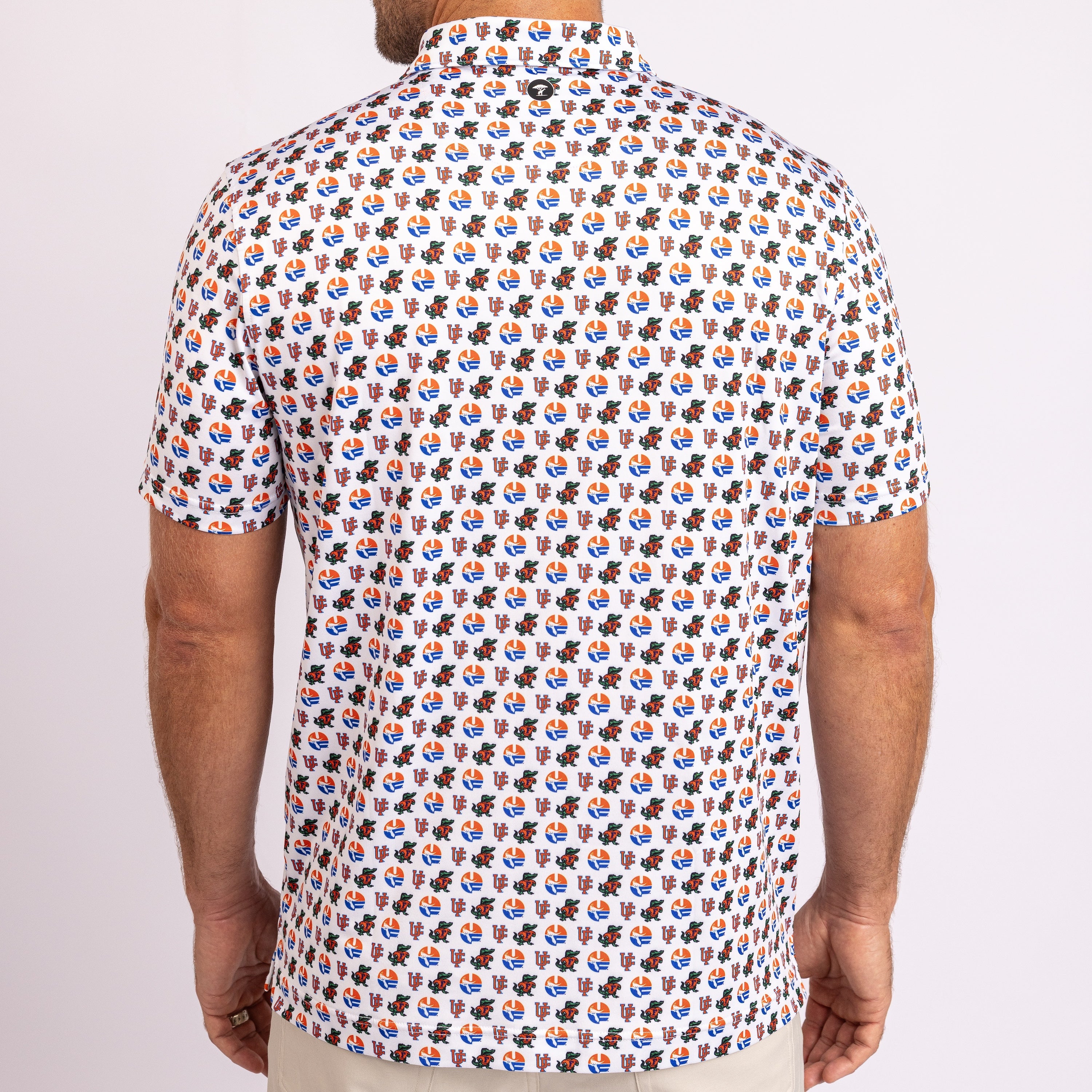 A man wearing a short-sleeve button-up shirt with an all-over repeating pattern of cartoon characters, shown from the back against a light gray studio background.