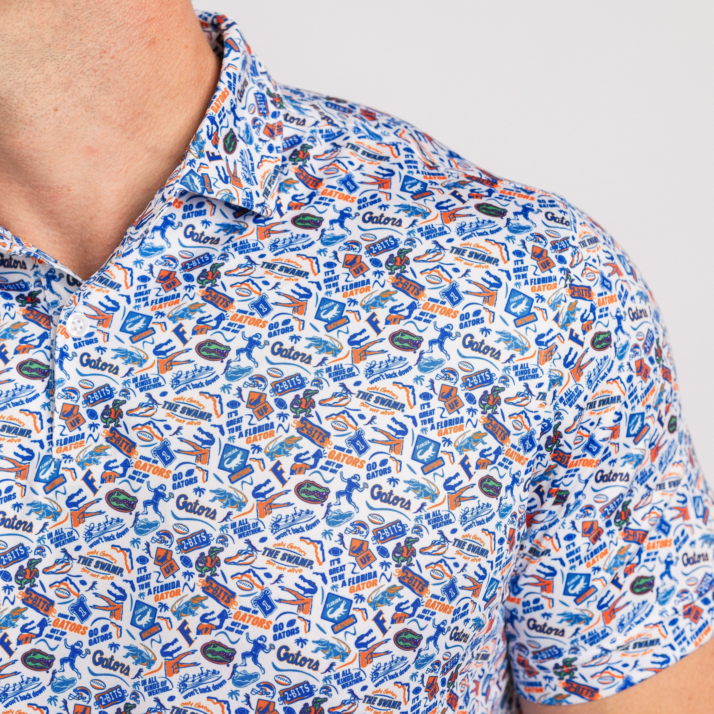 Close-up of a person wearing a patterned shirt with various logos and text.