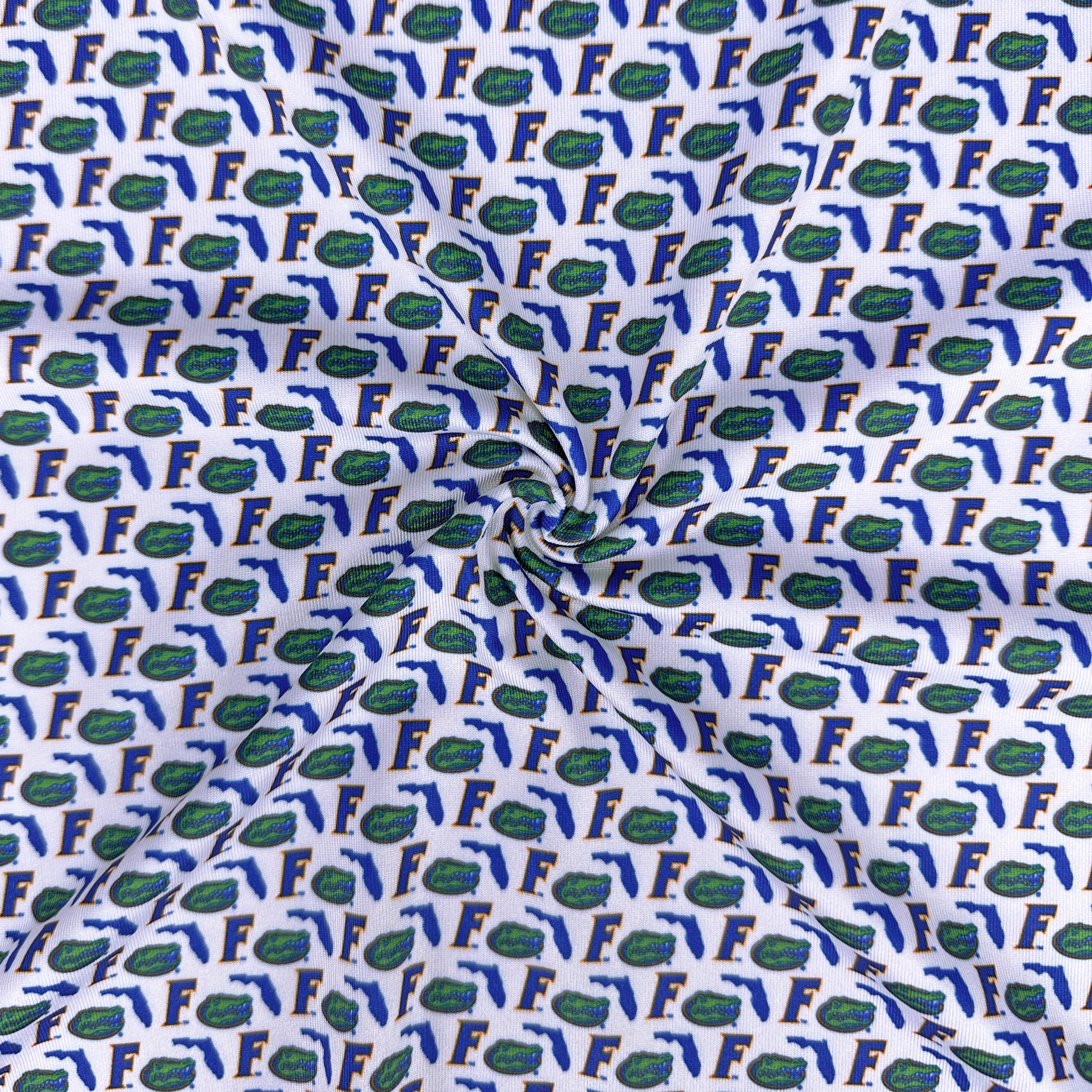 Fabric with a pattern of letters 'F' and alligator heads on a white background