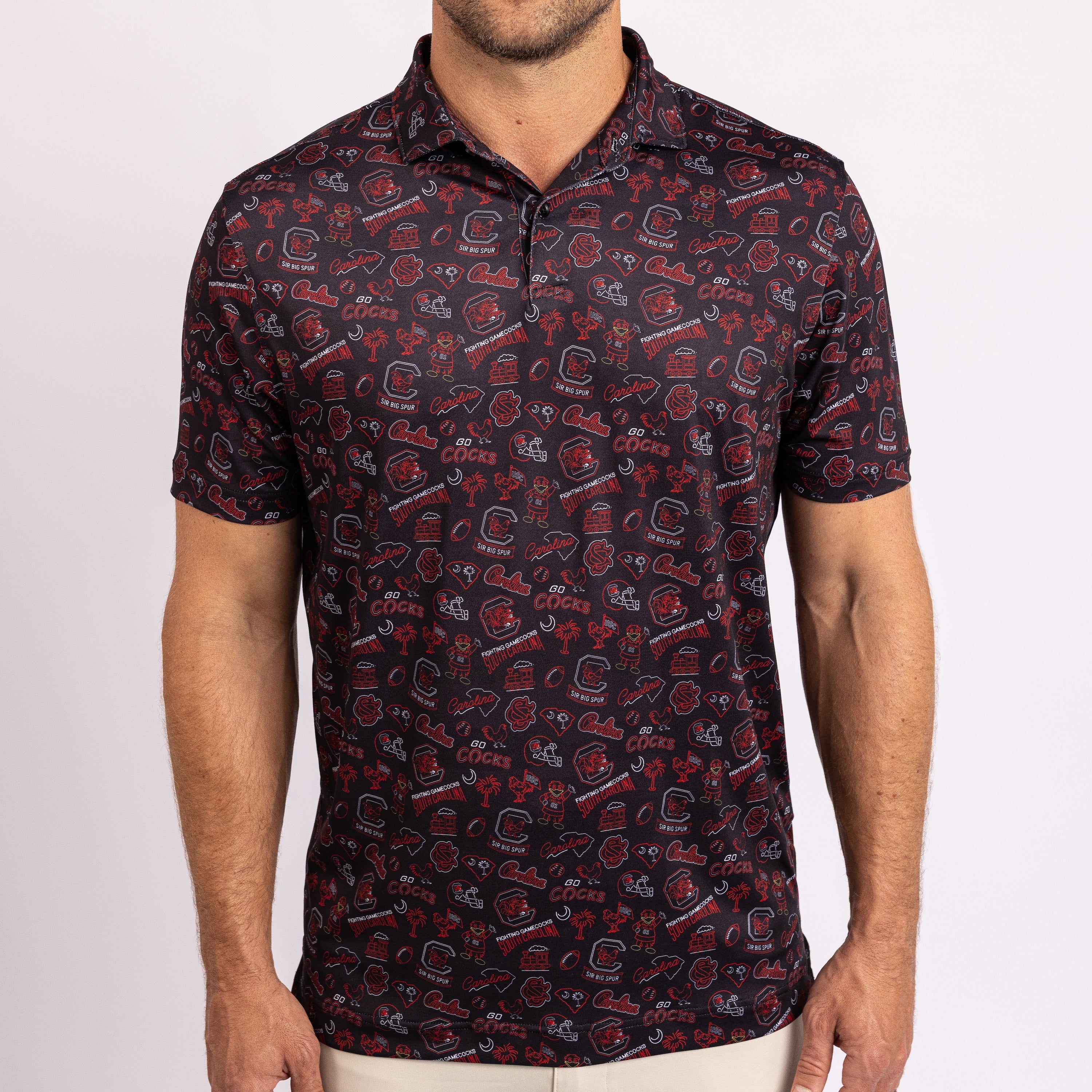 A man wearing a short-sleeve polo shirt with an all-over red, white, and black football helmet pattern, shown from the chin down against a light gray studio background.