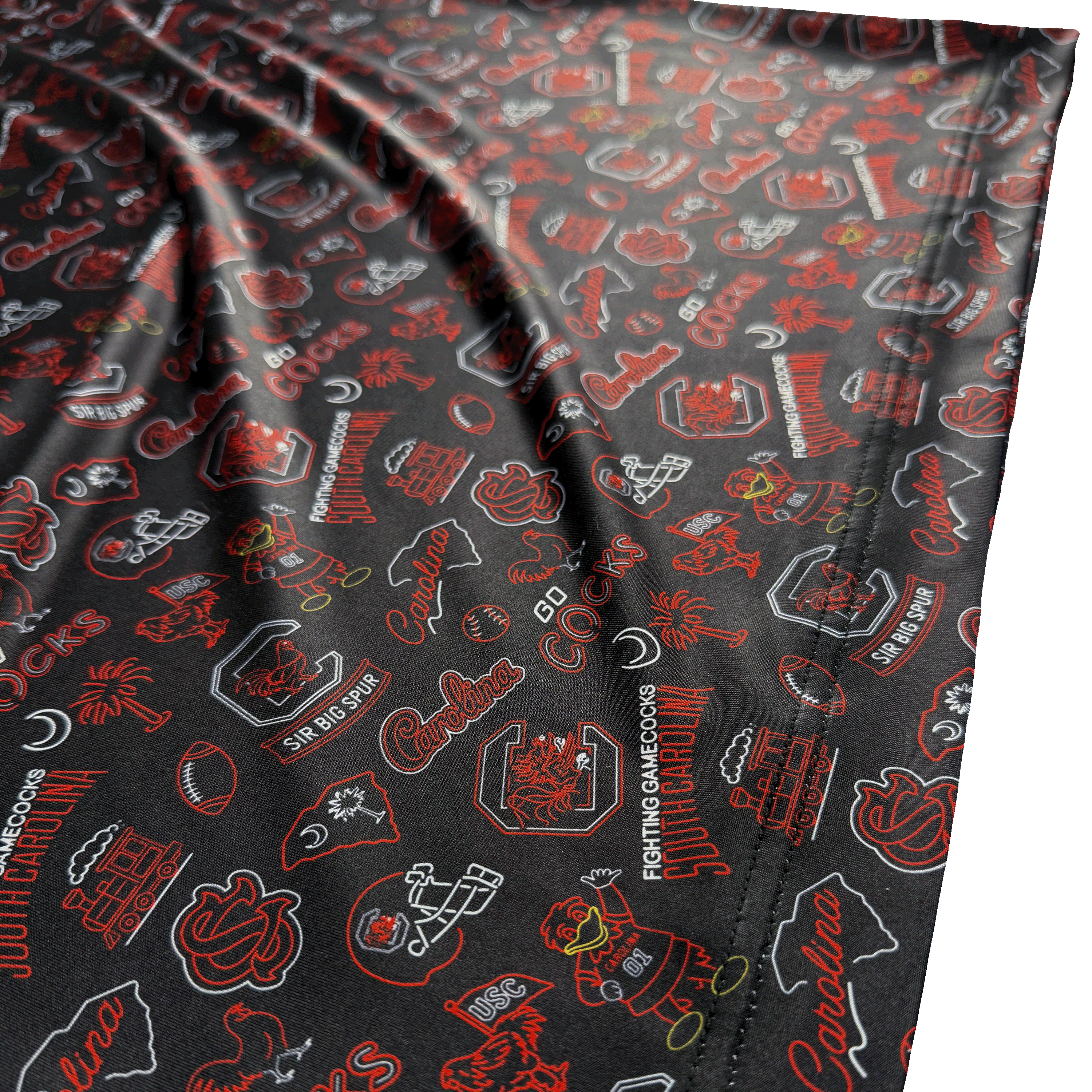 Close-up of a black athletic fabric with an all-over collegiate-style print in red and white, featuring logos and text including 'Cocks', 'South Carolina', and 'Sir Big Shog'.
