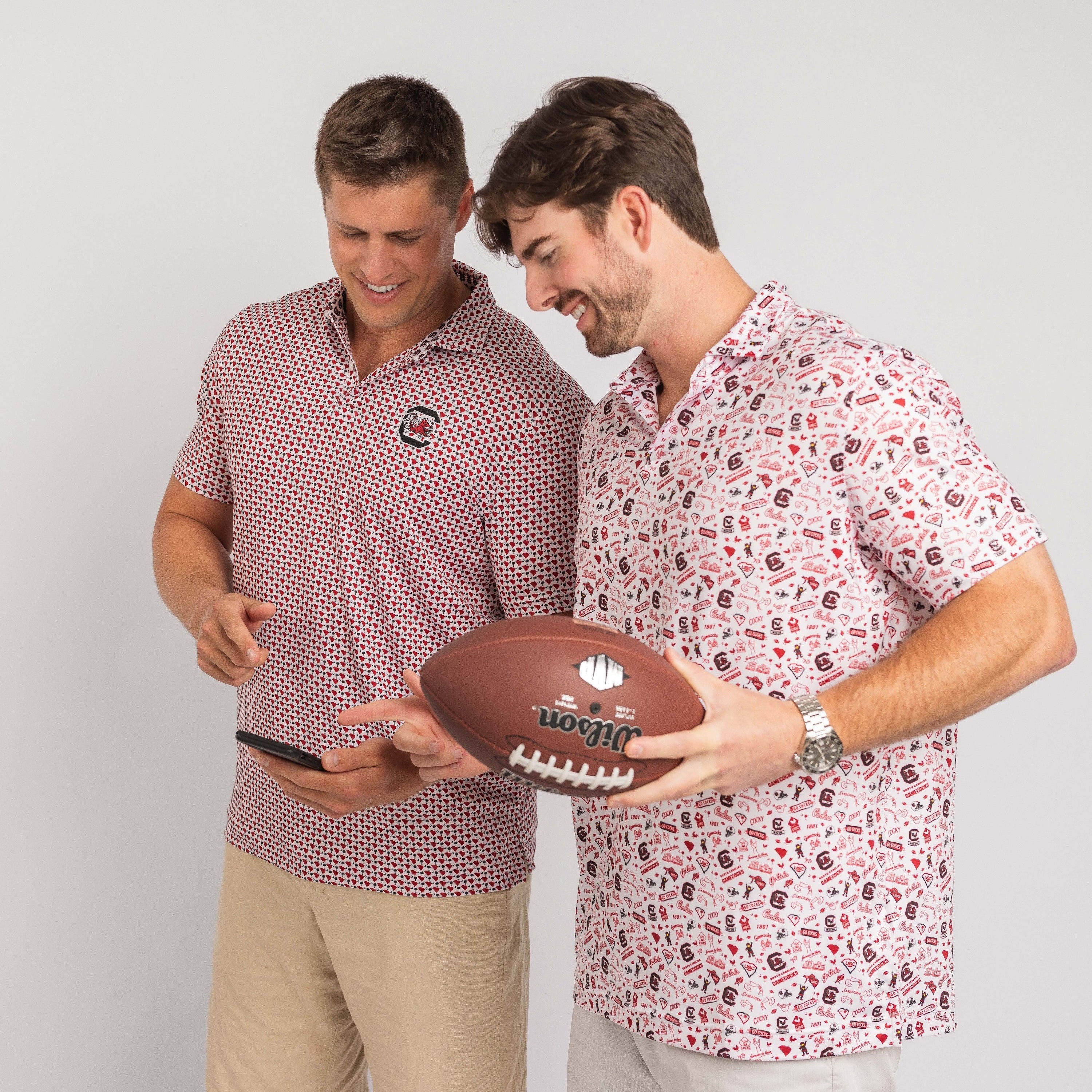 Two men wearing patterned shirts holding a football against a plain background